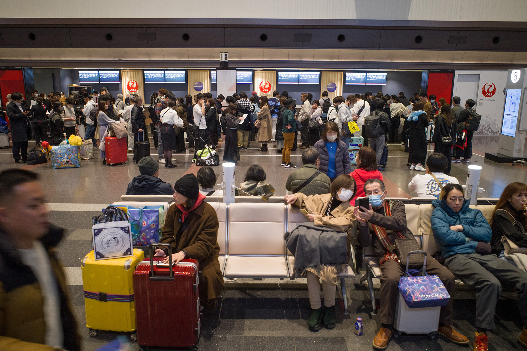 Travelers line up at a Japan Airlines service counter at Haneda International Airport in Tokyo, following flight cancellations due to an aircraft collision on Tuesday, January 2. 