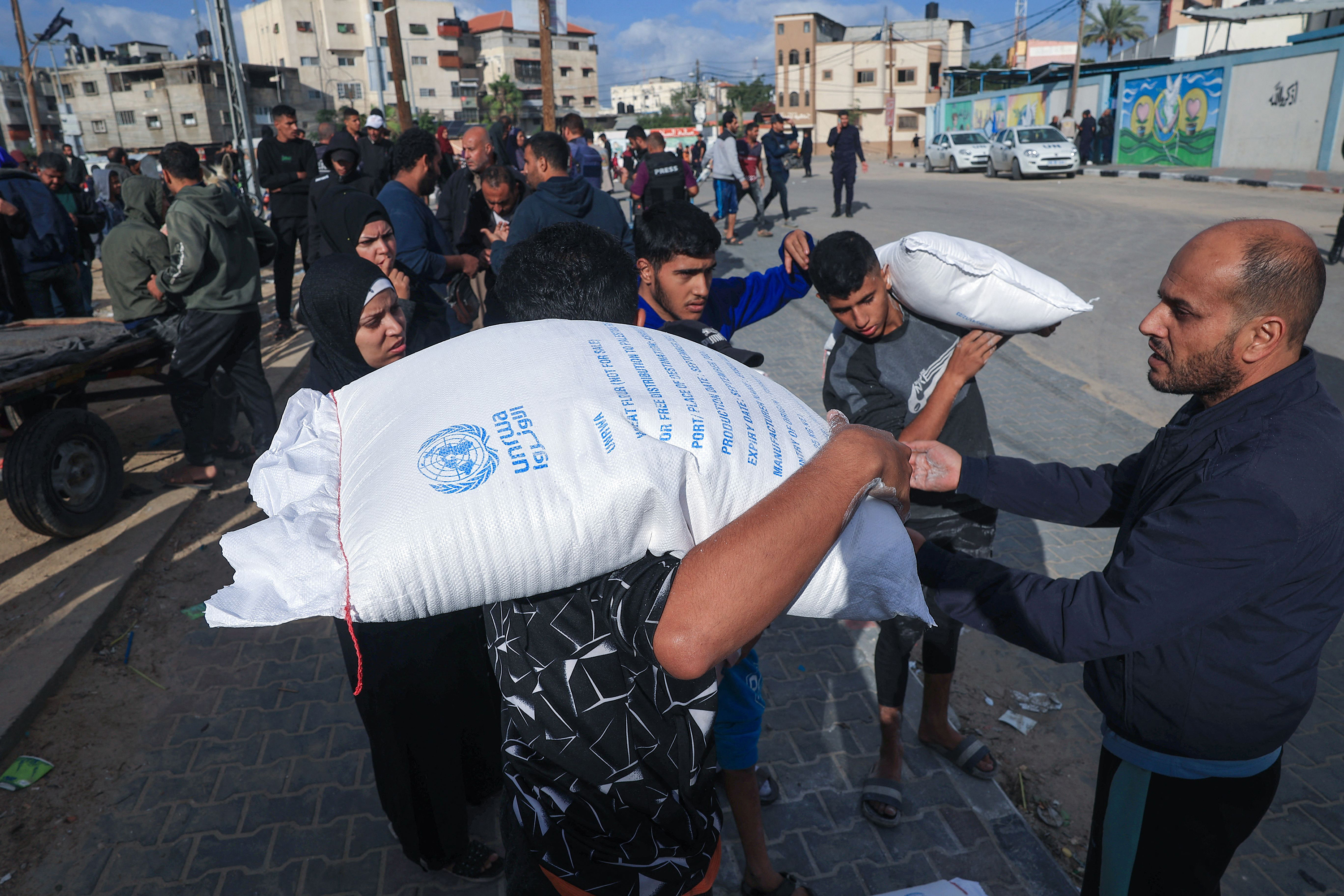 Palestinians receive bags of flour at the United Nations Relief and Works Agency for Palestine Refugees (UNRWA) distribution center in the Rafah refugee camp in southern Gaza on November 21, 2023.
