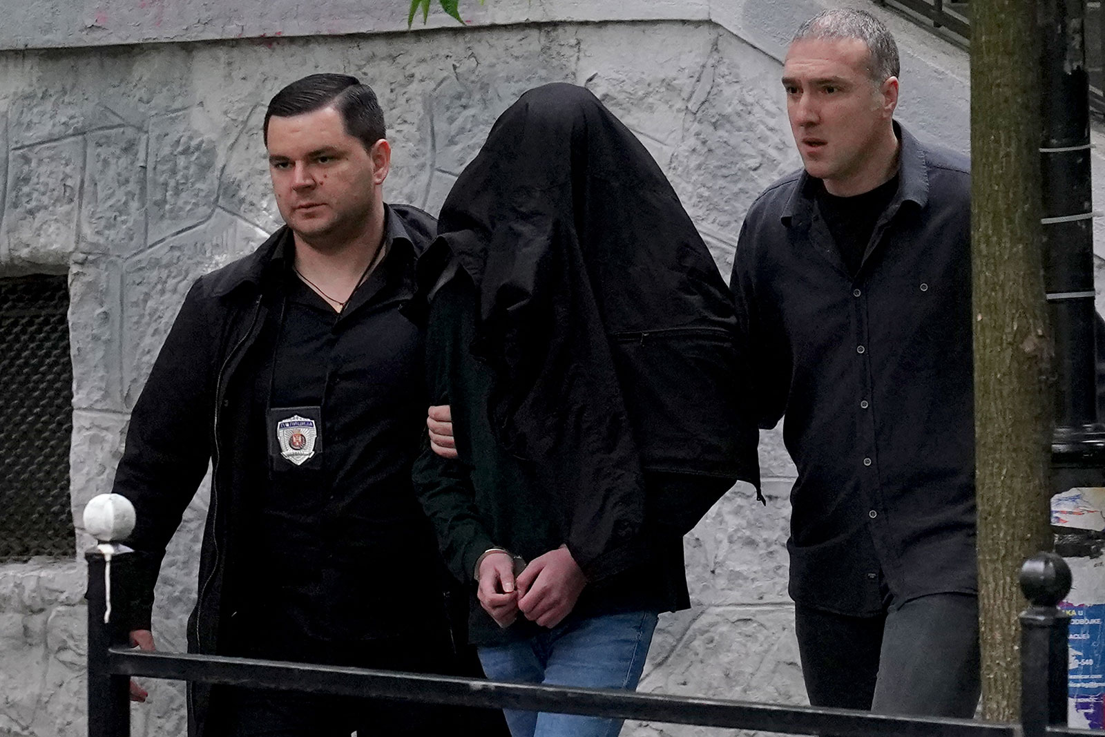 Police officers escort a person suspected of firing several shots at a school in the capital of Belgrade on May 3.