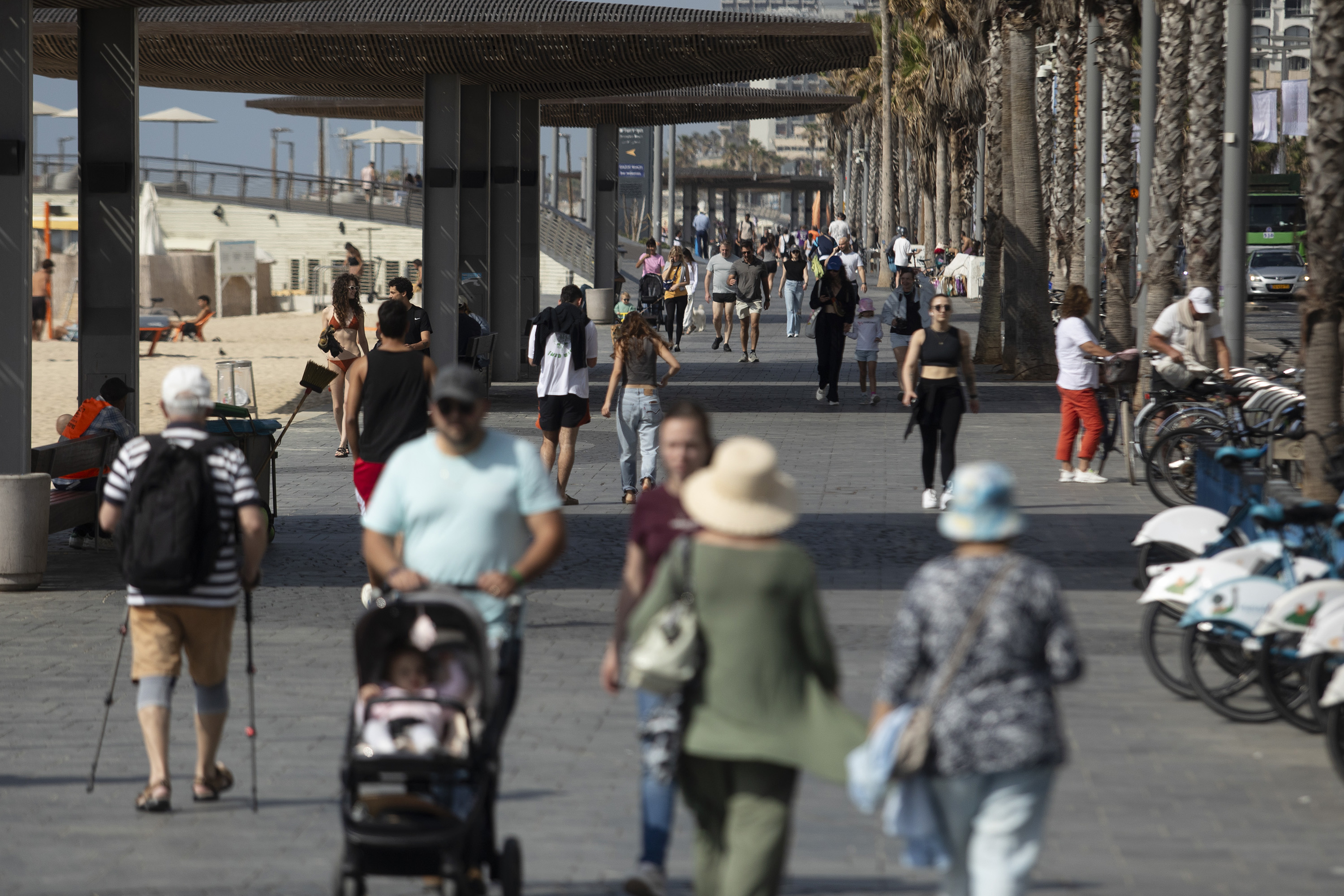 People walk a long a beach in Tel Aviv on April 14, following Iran's drone and missile attack.