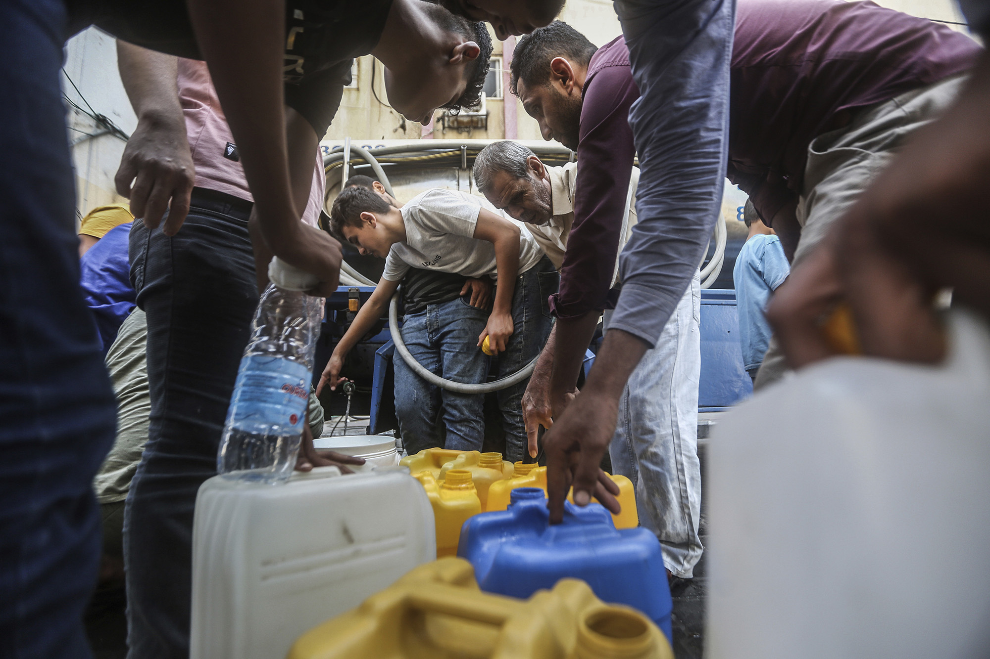 Palestinians fill containers with drinking water from a water distribution vehicle in Gaza City, Gaza, on October 12.