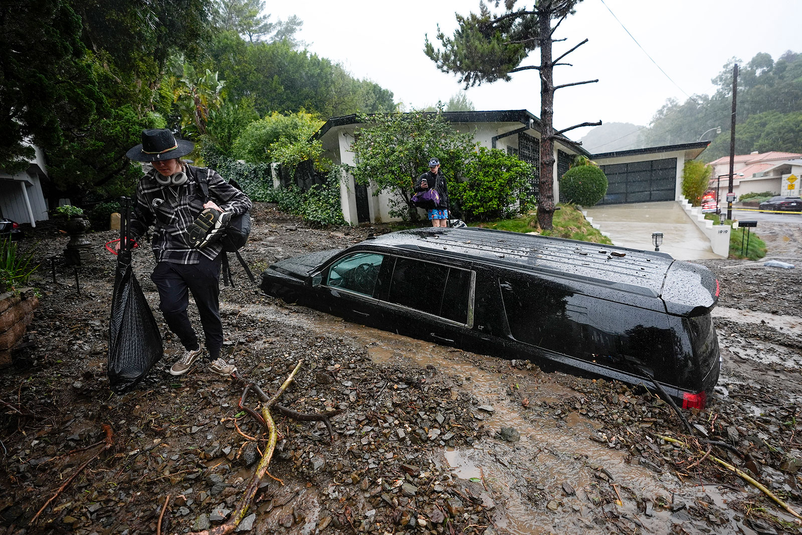 Residents evacuate past damaged vehicles after storms caused a mudslide in the Beverly Crest area of Los Angeles on Monday. 