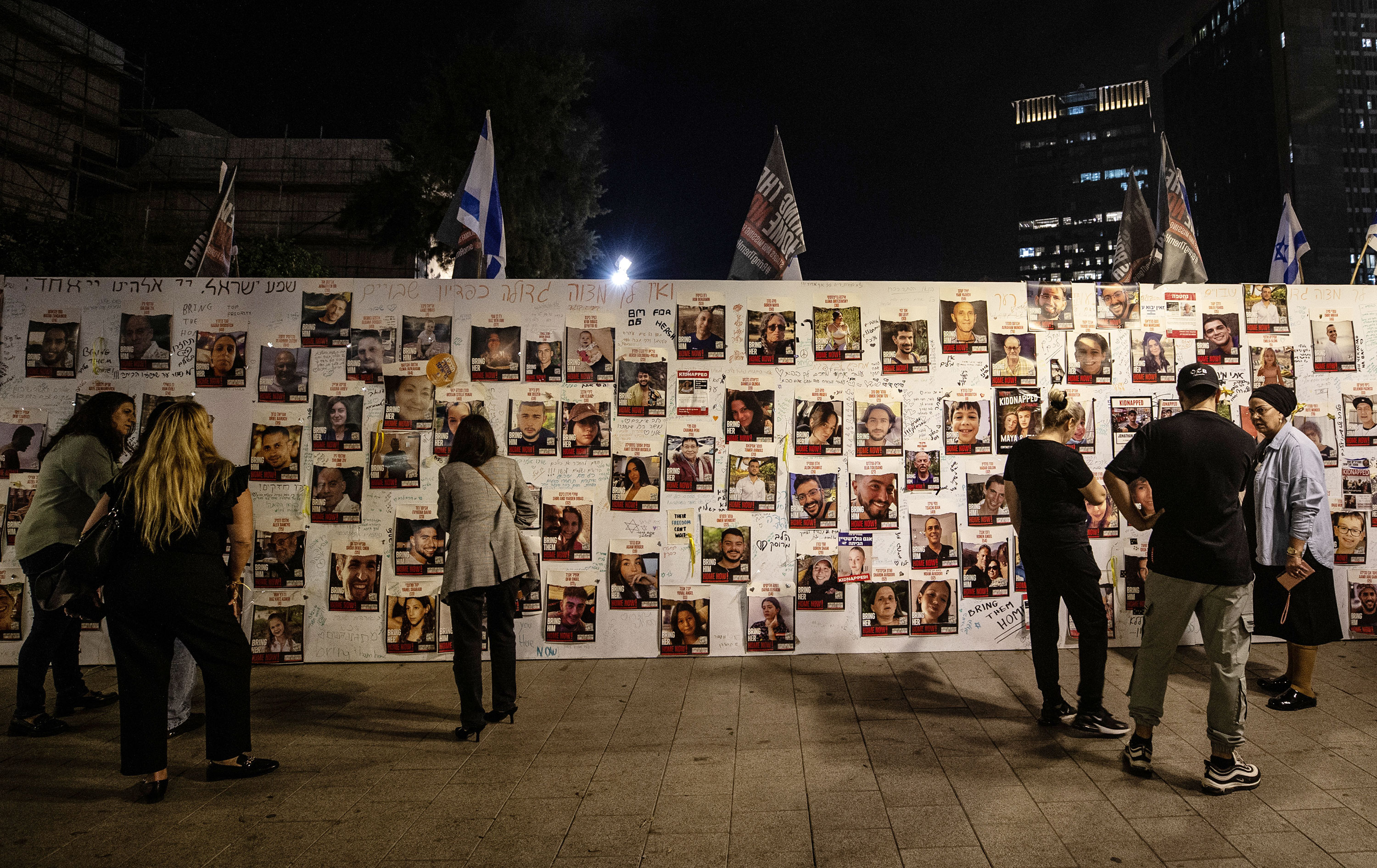 People look at photographs of hostages captured by Hamas posted on a wall in Tel Aviv, Israel, on November 13. 