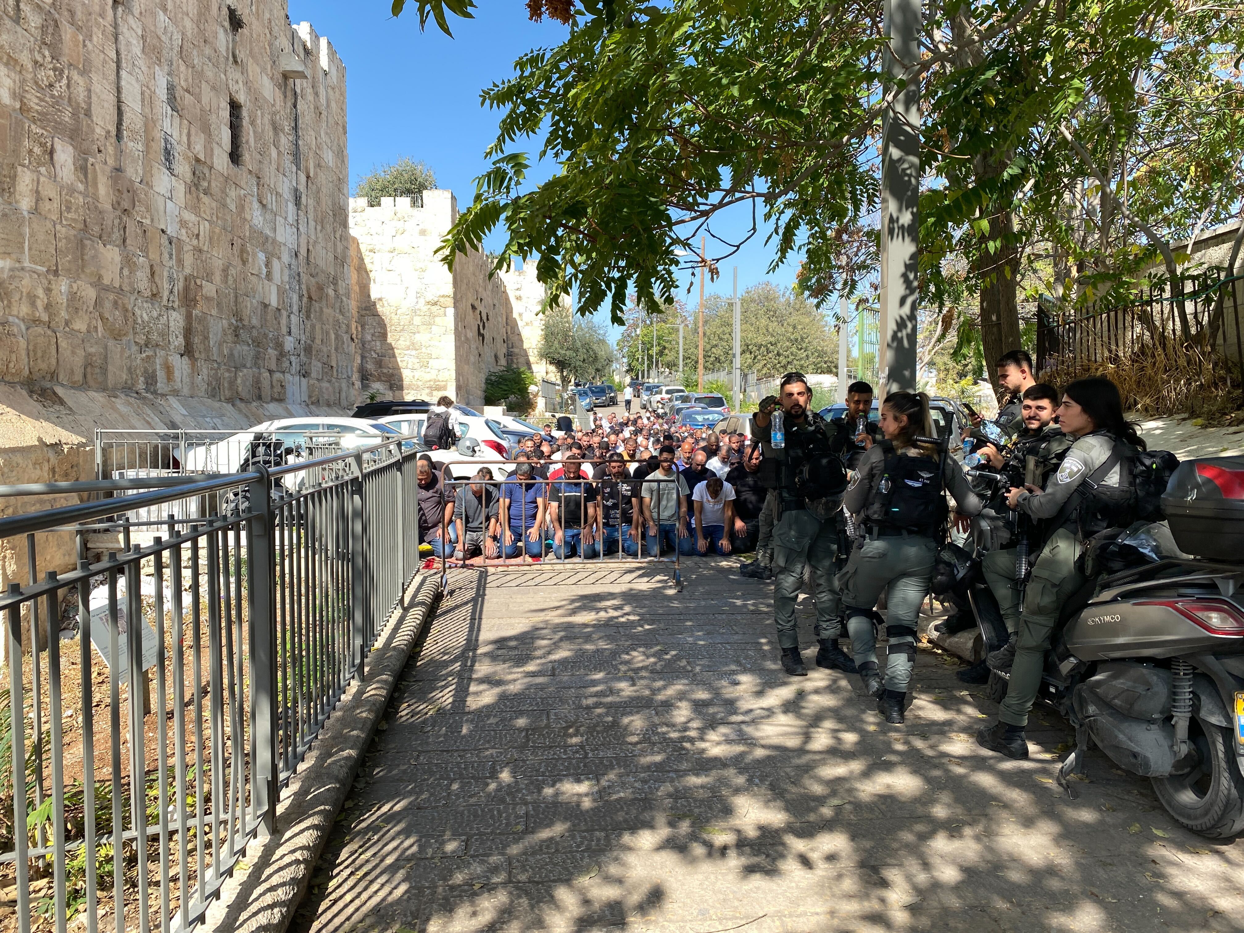 People praying outside the gates of the old city after not being allowed to enter.