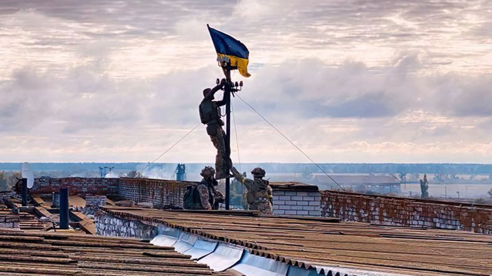 Ukrainian troops hoist a flag above a building in Vysokopillia, in southern Kherson region.