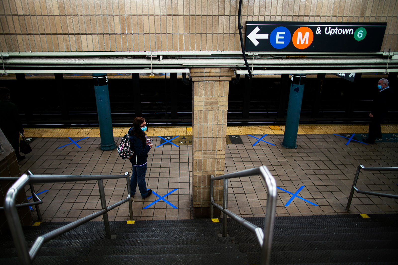 People wearing protective face masks practice social distancing as they wait on marked spots at a subway station during the Covid-19 pandemic on May 12, in New York City. 