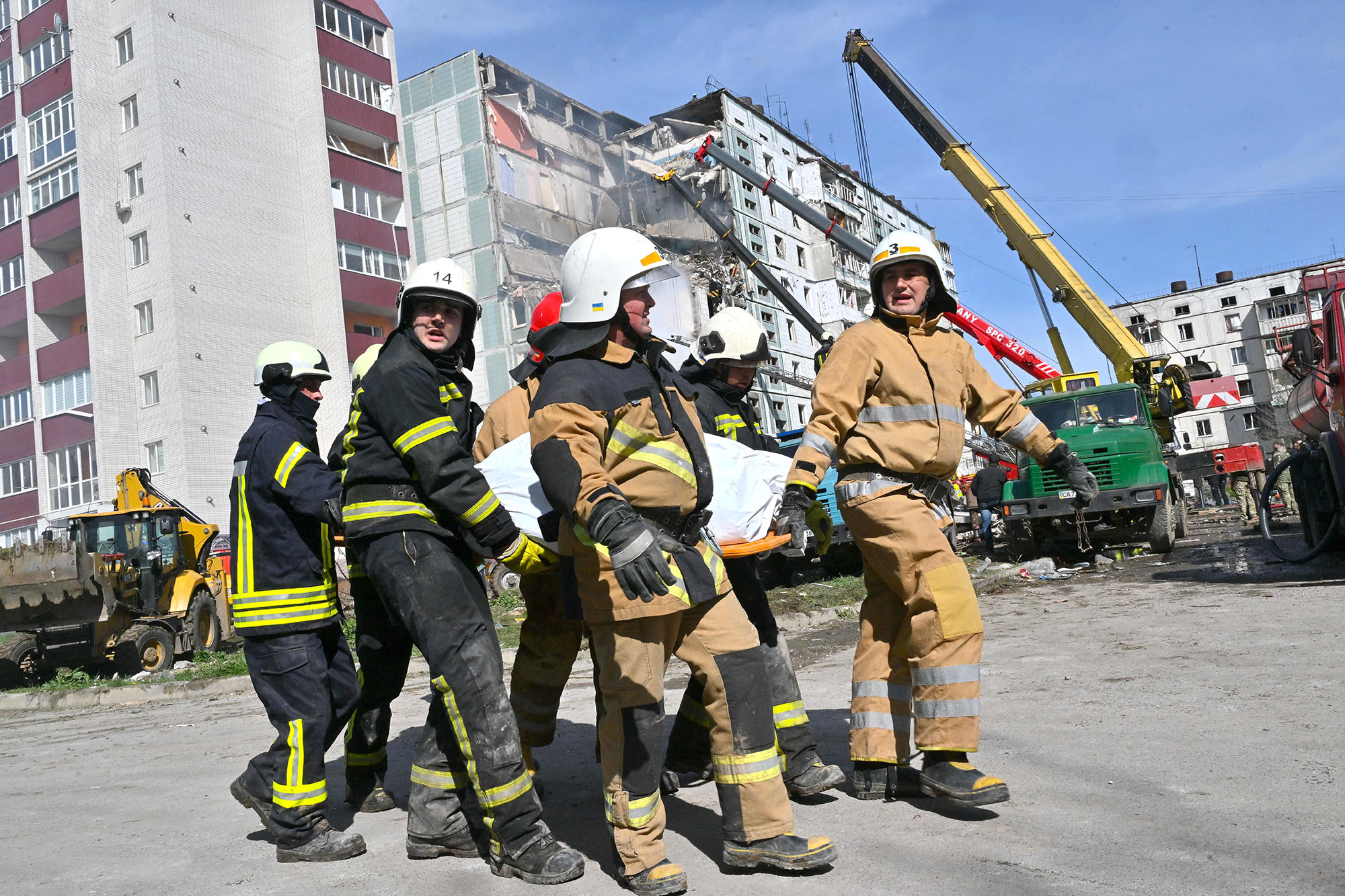 Rescuers carry a bag containing a body next to damaged residential building in Uman, south of Kyiv, Ukraine, on April 28.
