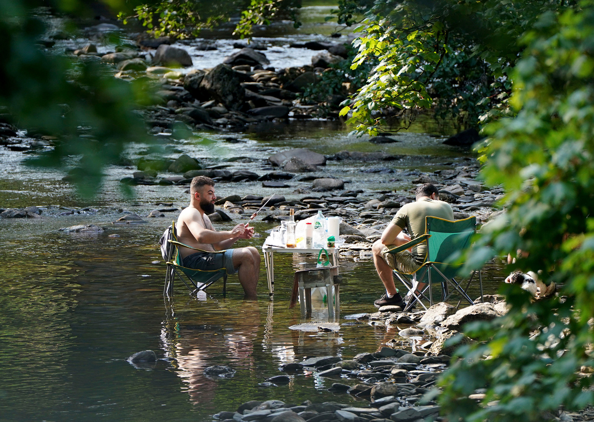 People escape the heatwave by taking a barbecue in a river near the village of Luss in Argyll and Bute on the west bank of Loch Lomond, Scotland, Monday, July 18.