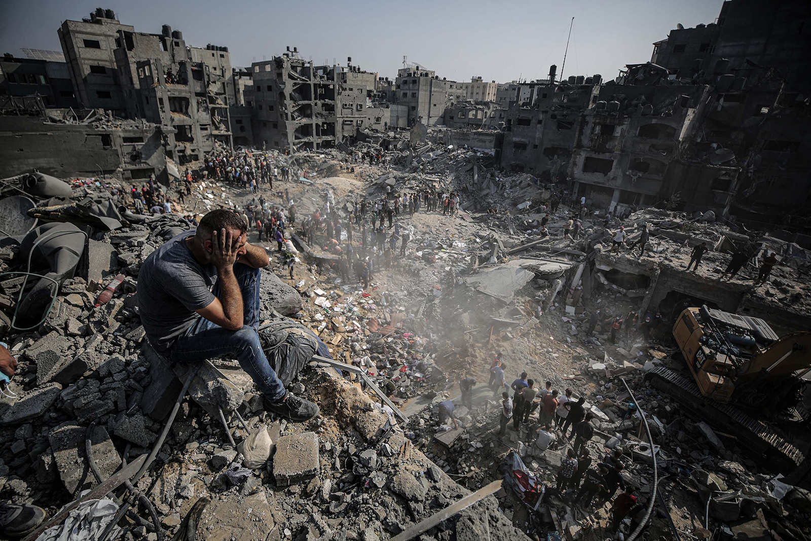 A man sits on debris as Palestinians conduct a search and rescue operation after the second bombardment of the Jabalya refugee camp in Gaza City, on Wednesday, November 1. 