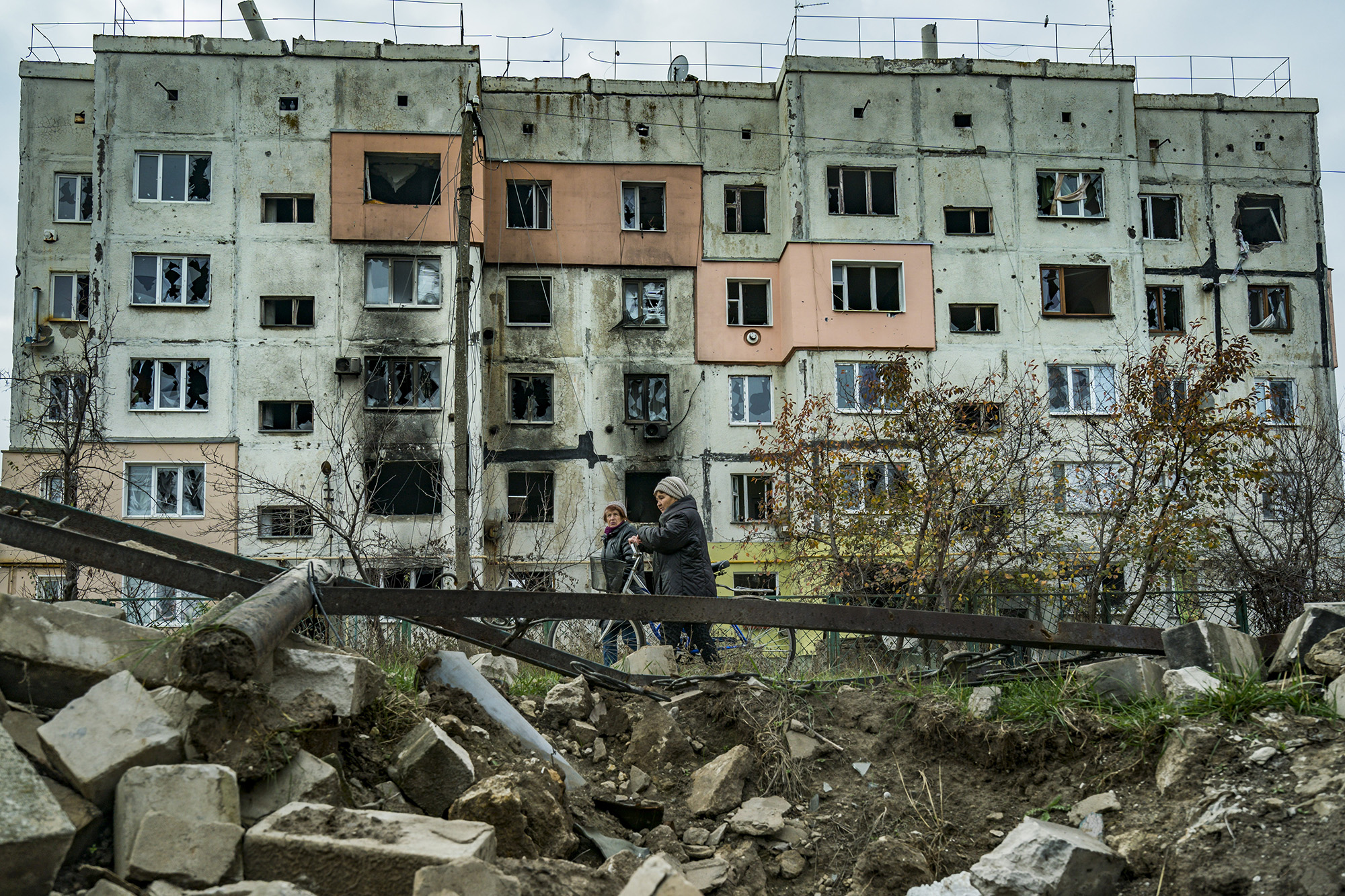 A couple of women walk past a destroyed building in Arkhanhelske, Kherson, after the recent withdrawal of Russian troops, November 9.