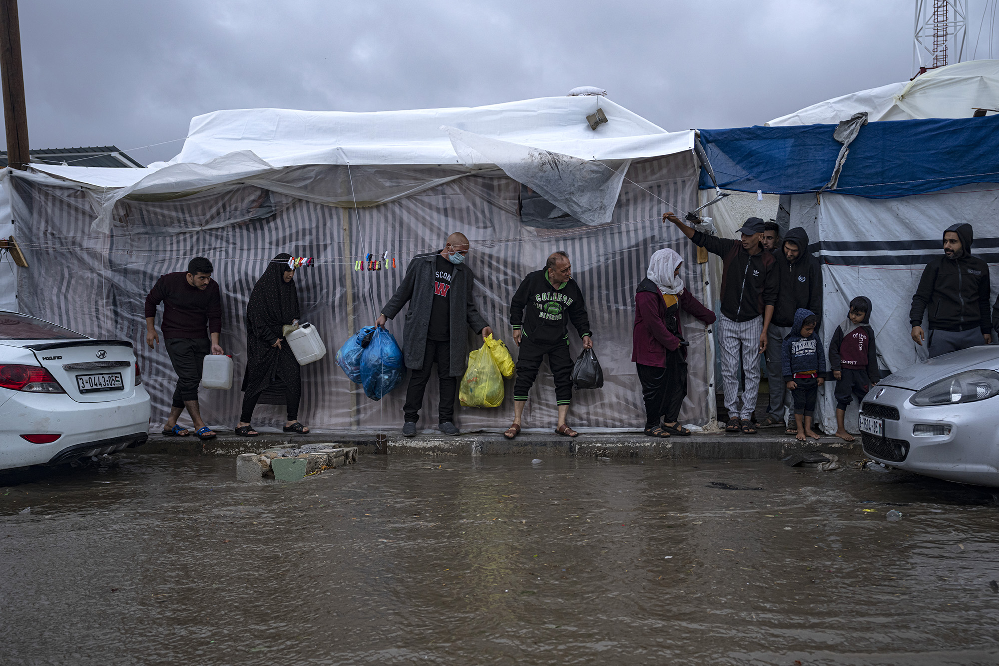 Palestinians seek cover from a rainfall at a UN tent camp in the southern town of Khan Younis, Gaza, on November 19.