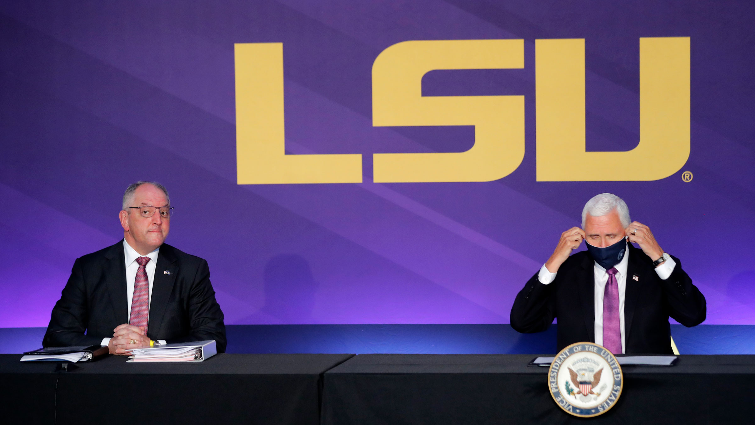 Vice President Mike Pence takes off his mask to speak with Louisiana Gov. John Bel Edwards, left, at a roundtable discussion Tuesday in Baton Rouge, Louisiana.