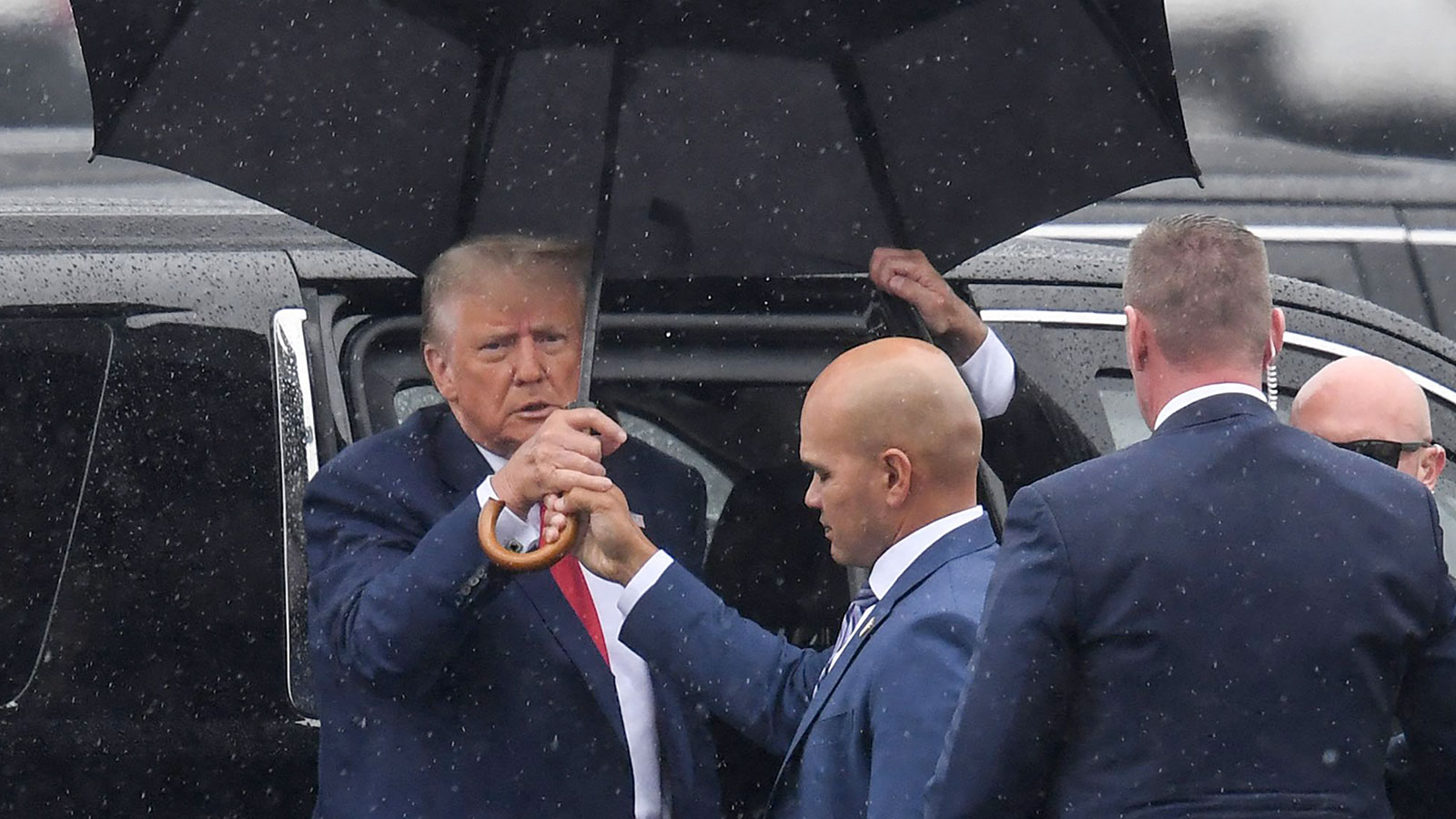 Walt Nauta hands Trump an umbrella as he arrives to Ronald Reagan Washington National Airport in Arlington, Virginia, on August 3, after his arraignment in court. 