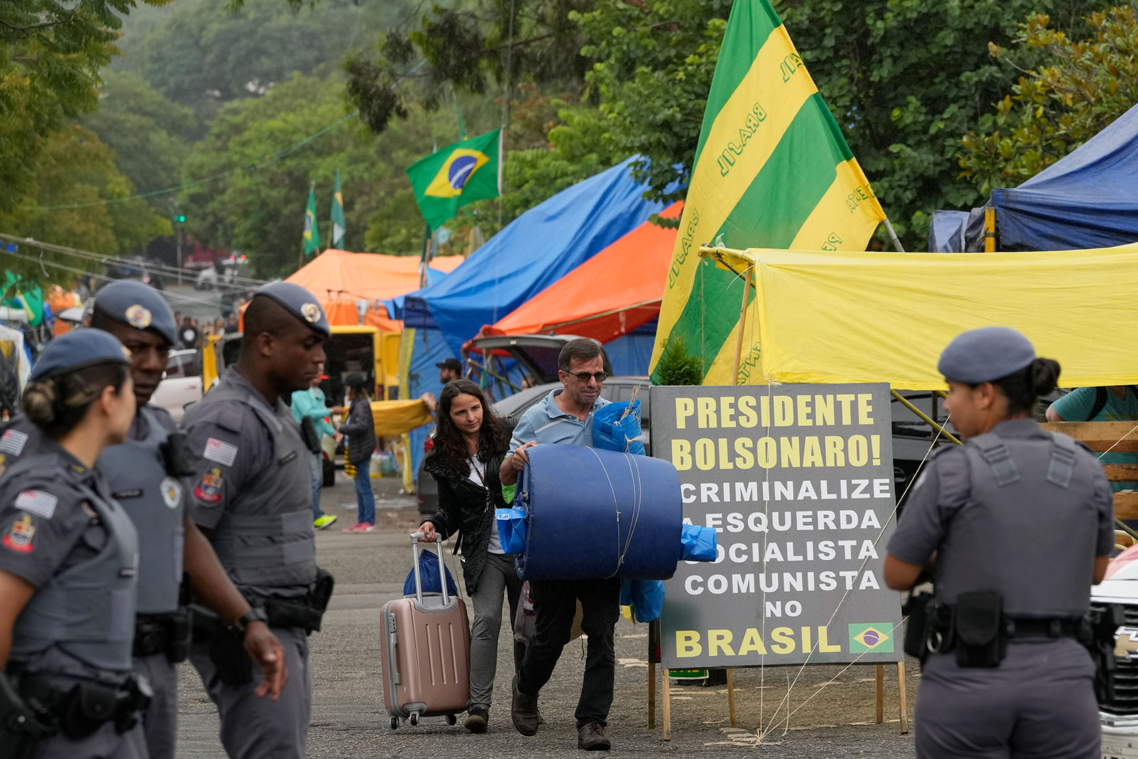 Supporters of former Brazilian President Jair Bolsonaro leave their encampment outside army headquarters as military police stand watch in Sao Paulo, Brazil, on Monday. 