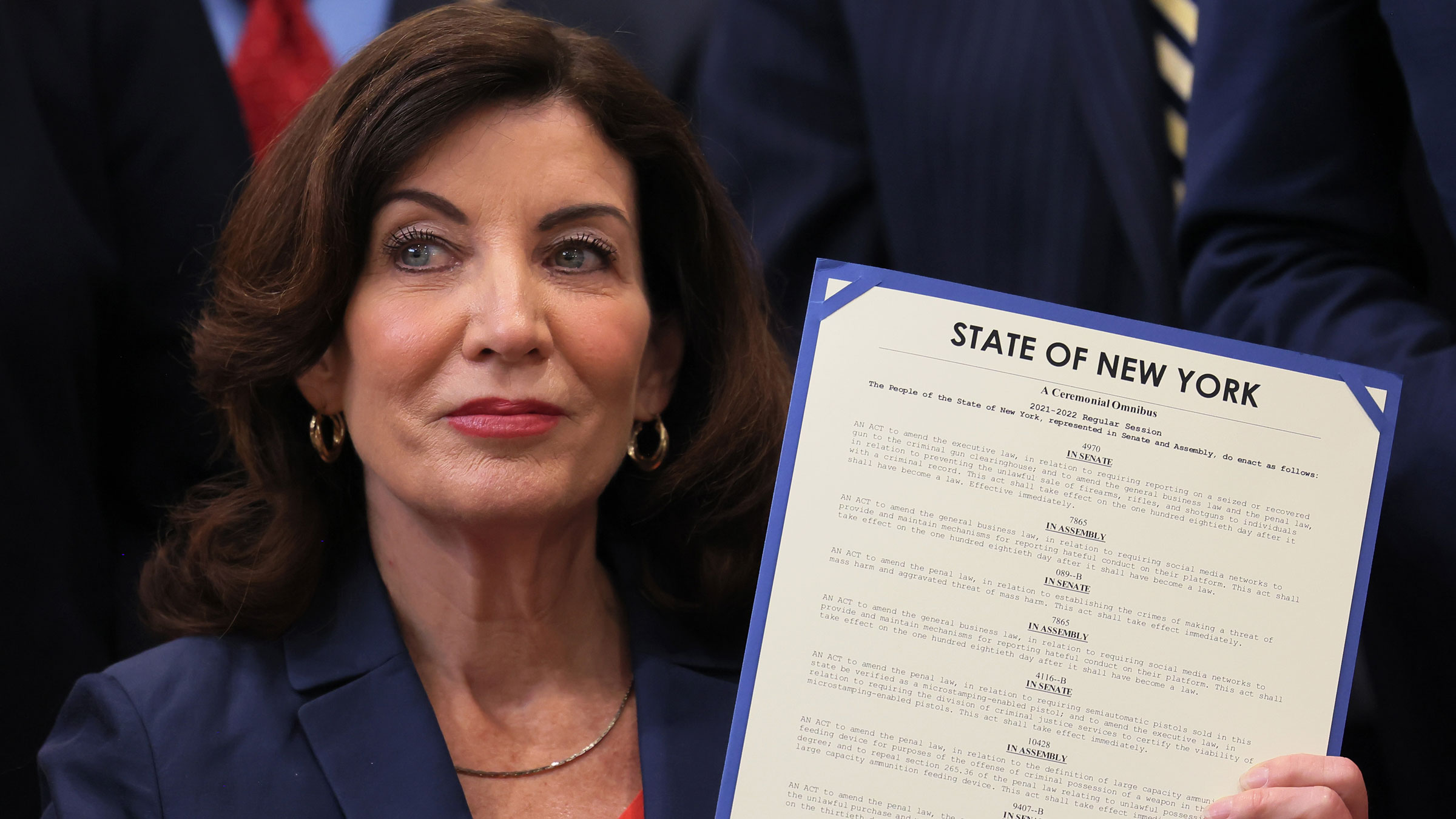 New York Gov. Kathy Hochul holds up signed legislation as she is surrounded by lawmakers on Monday.