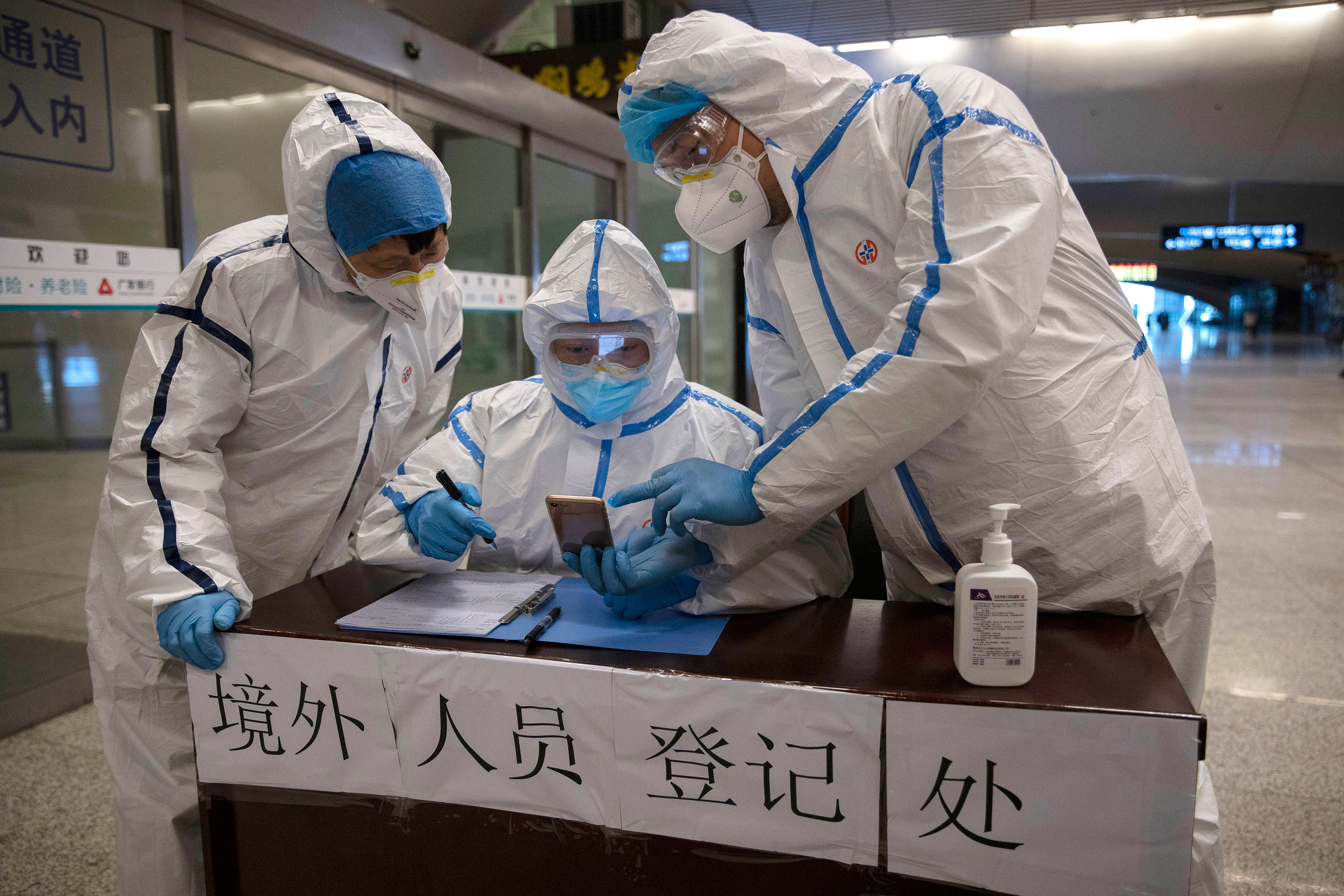 Health workers check details of a passenger arriving at a train station in Wuhan, China on March 29.