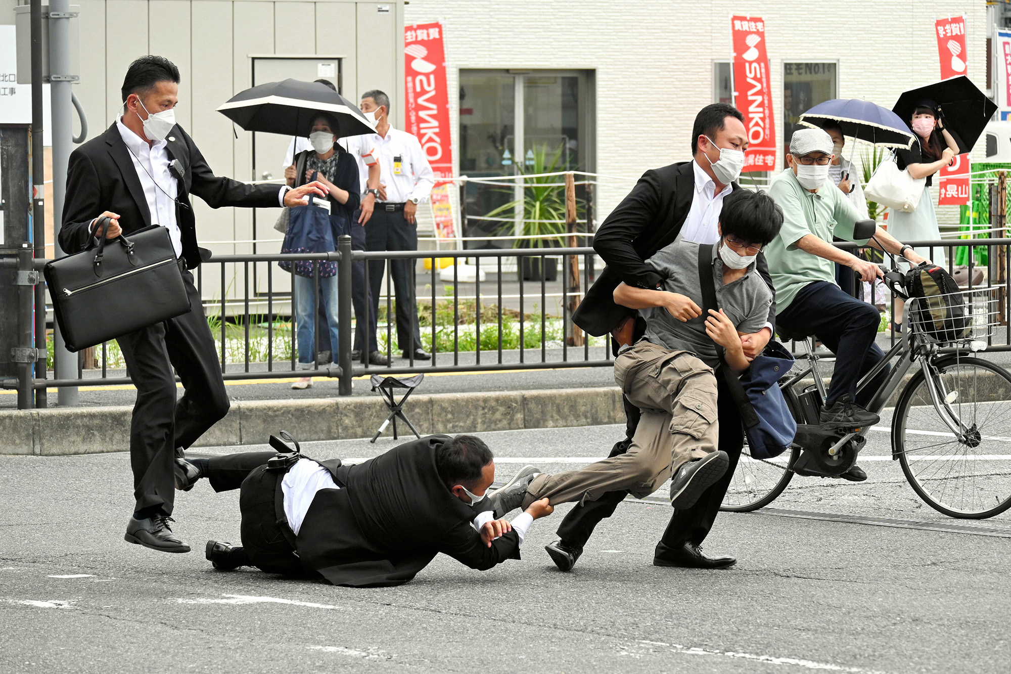Security police tackle to arrest a suspect who is believed to have shot former Prime Minister Shinzo Abe in front of Yamatosaidaiji Station on July 8.