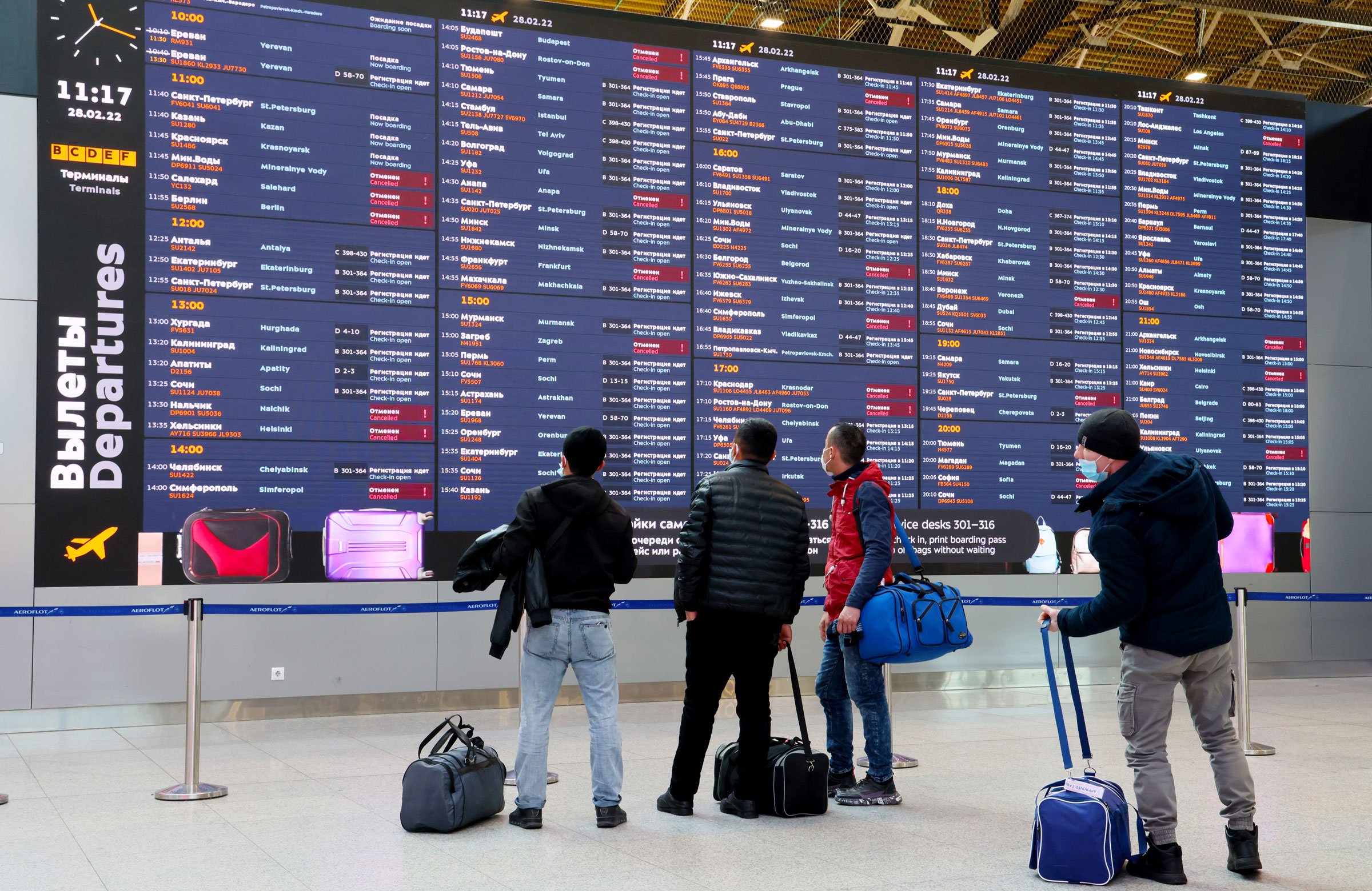 Travelers look at a departures board Monday at the Sheremetyevo International Airport in Moscow. The flights in red were canceled.