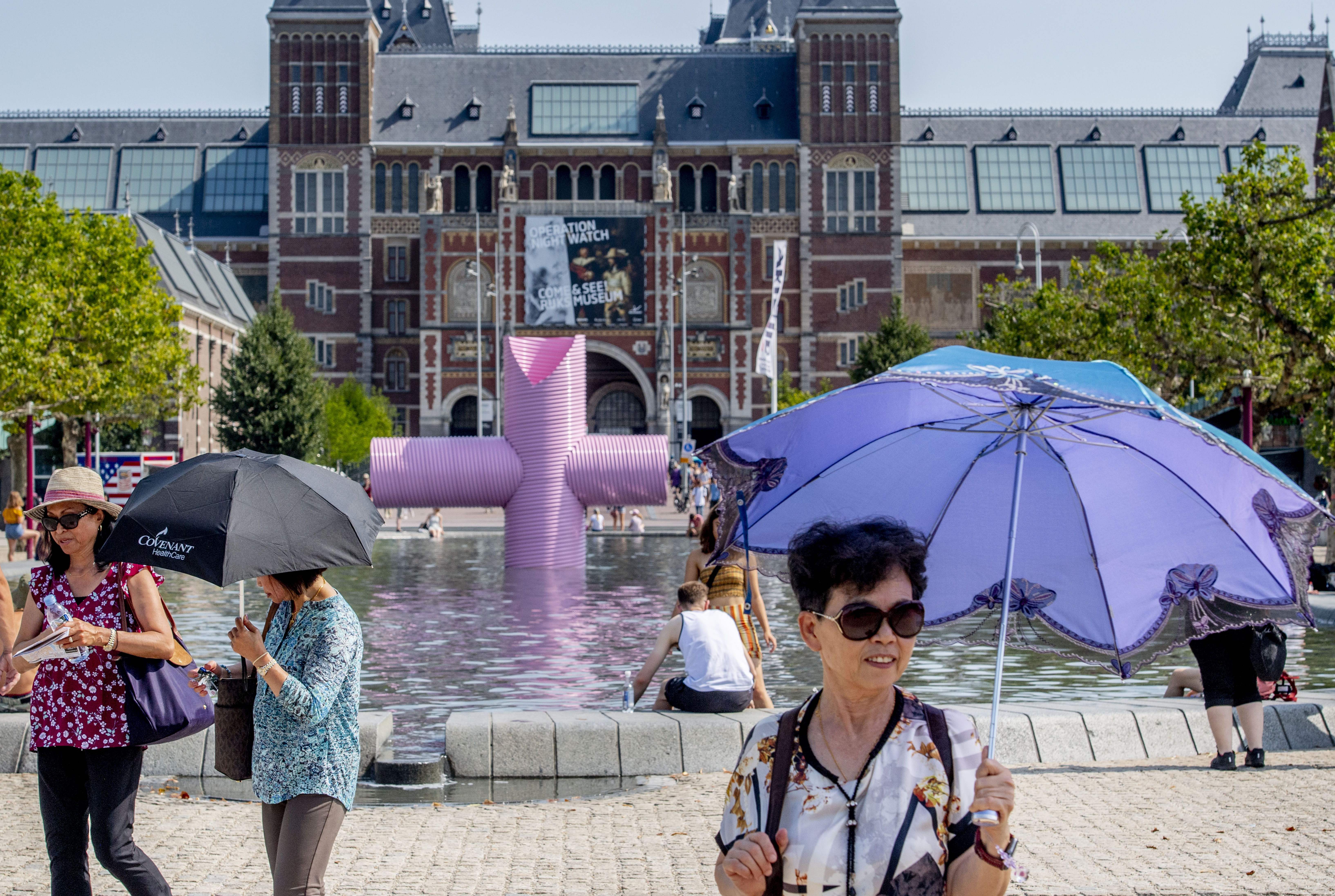 A woman holds an umbrella to protect herself from the sun as she walks past the Rijksmuseum in Amsterdam on Thursday. 