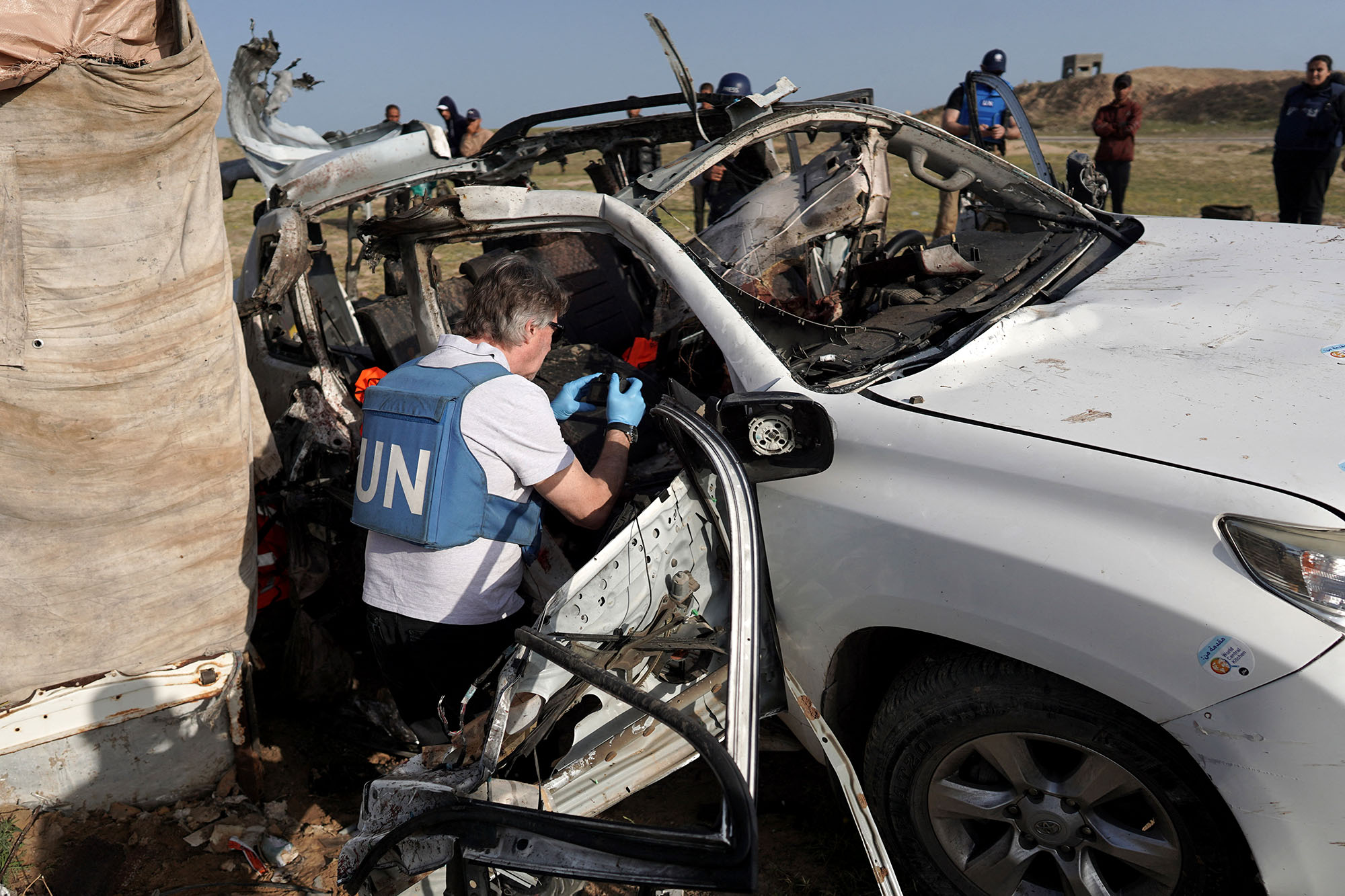 United Nations staff members inspect the carcass of a car used by aid group World Central Kitchen that was hit by an Israeli strike the previous day in Deir al-Balah, central Gaza, on April 2.