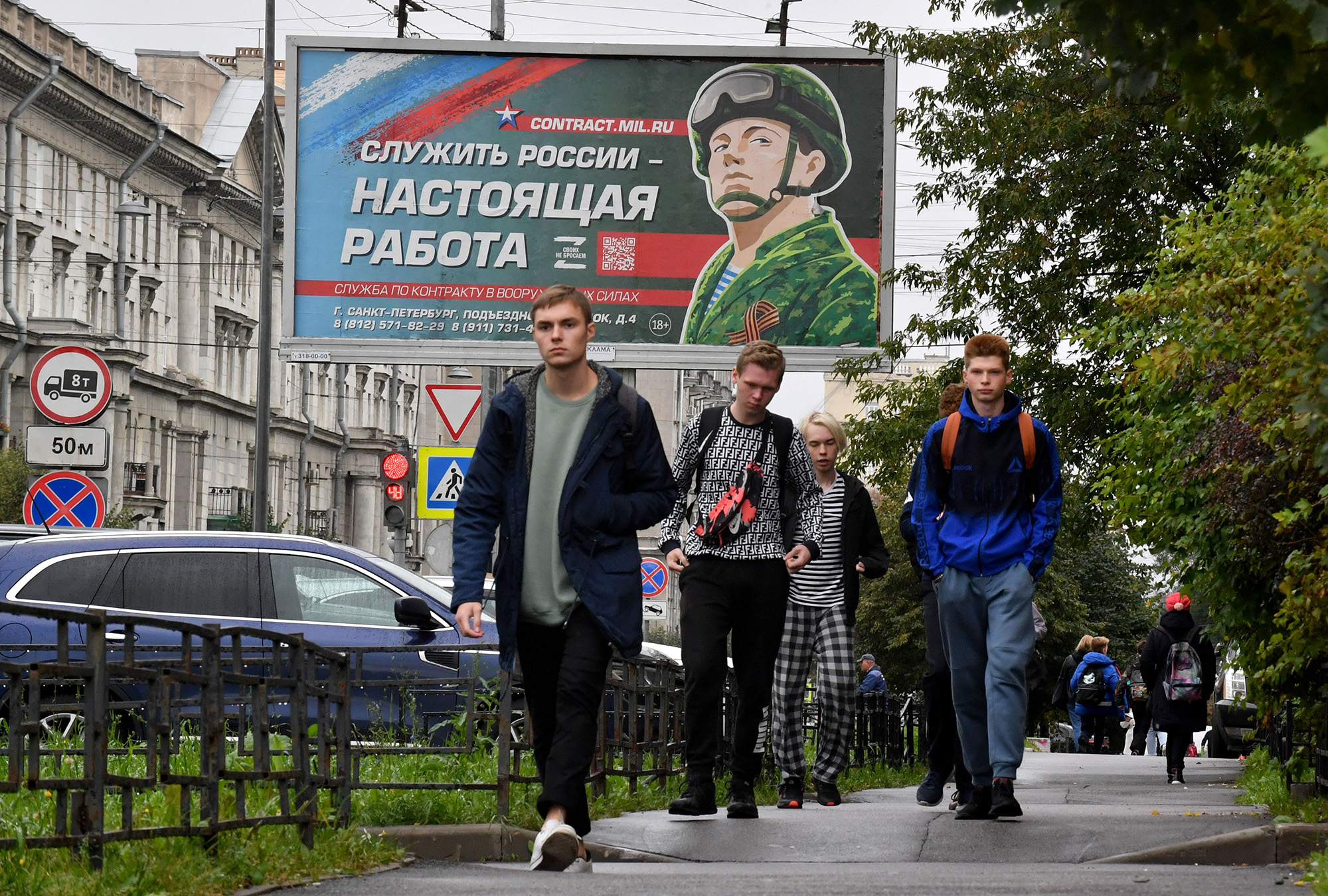 Young men walk in front of a billboard promoting contract army service in Saint Petersburg, Russia, on September 29.