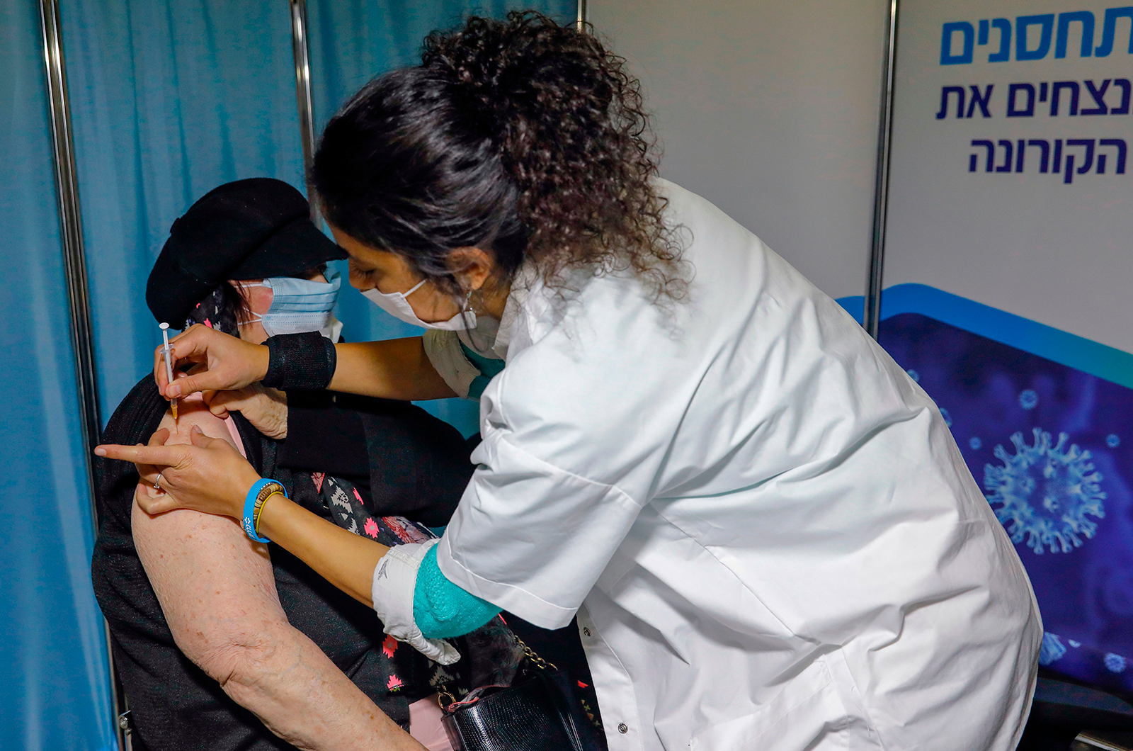 A Israeli healthcare worker administers a Covid-19 vaccine to a woman at the Kupat Holim Clalit clinic in Jerusalem, on January 14
