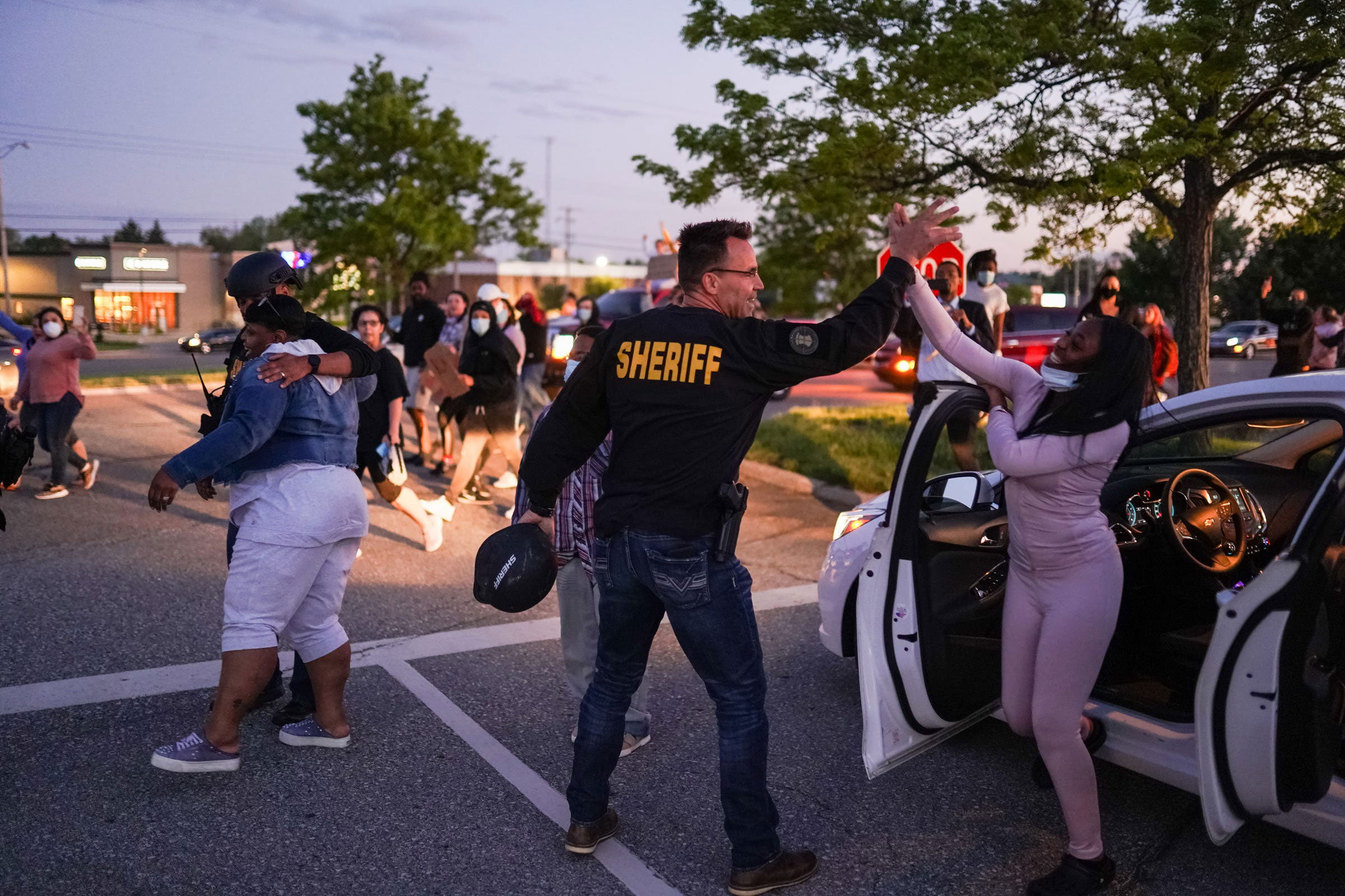 Genesee County Sheriff Chris Swanson high fives a woman who called his name as he marches with protesters in Flint, Michigan, on May 30.