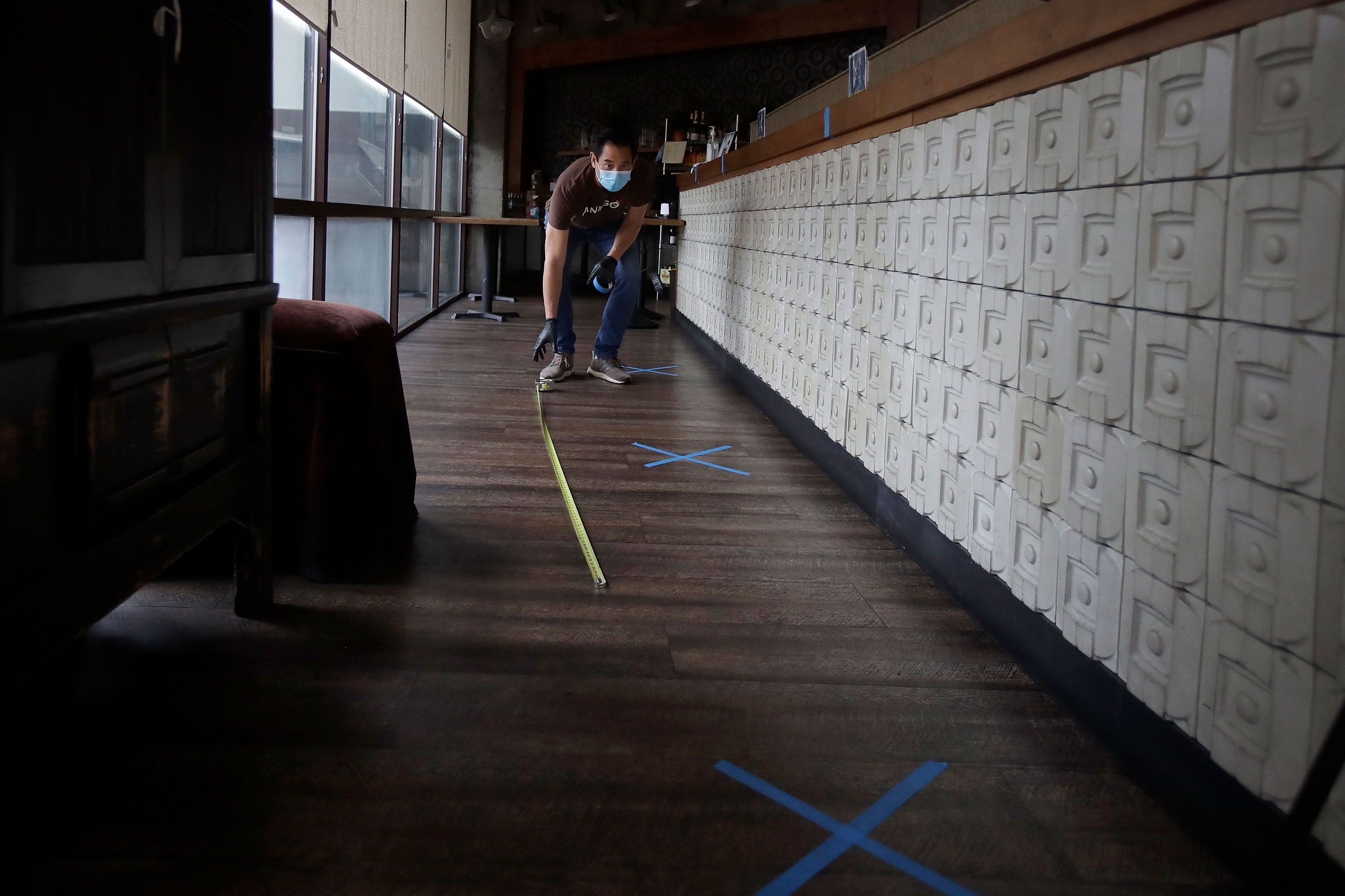 Kenneth Lew, managing member at Crustacean Restaurant, measures distances for people to stand while waiting for takeout at the restaurant in San Francisco on May 12. 
