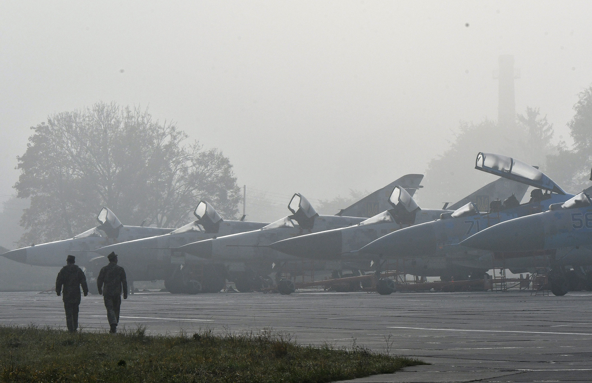 Ukrainian servicemen walk in front of Ukrainian SU-24 and SU-27 military planes during an air force exercises on Starokostyantyniv military airbase on October 12, 2018.
