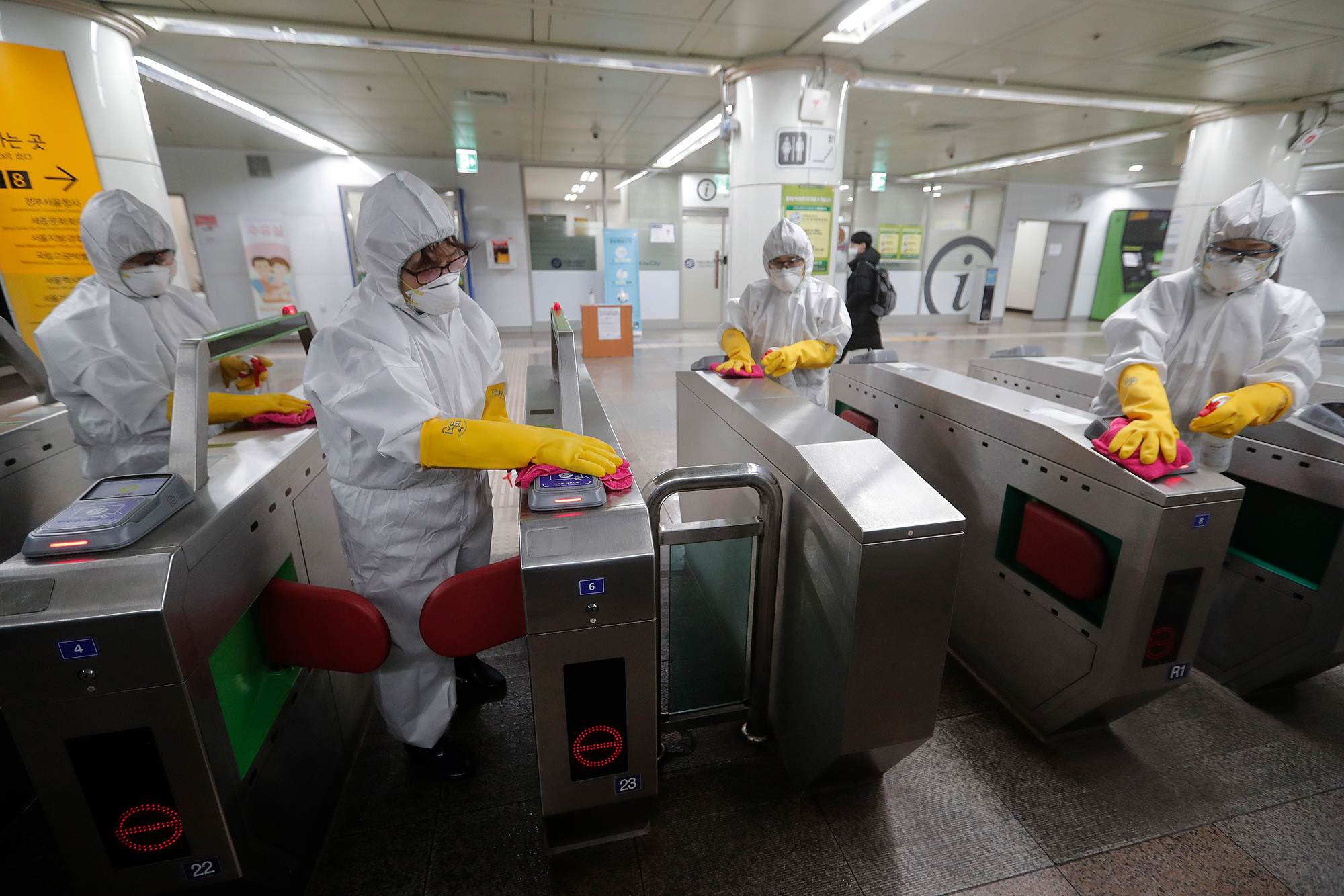 Workers wearing protective gear disinfect ticket gates as a precaution against the coronavirus at a subway station in Seoul, South Korea, Friday, February 28.