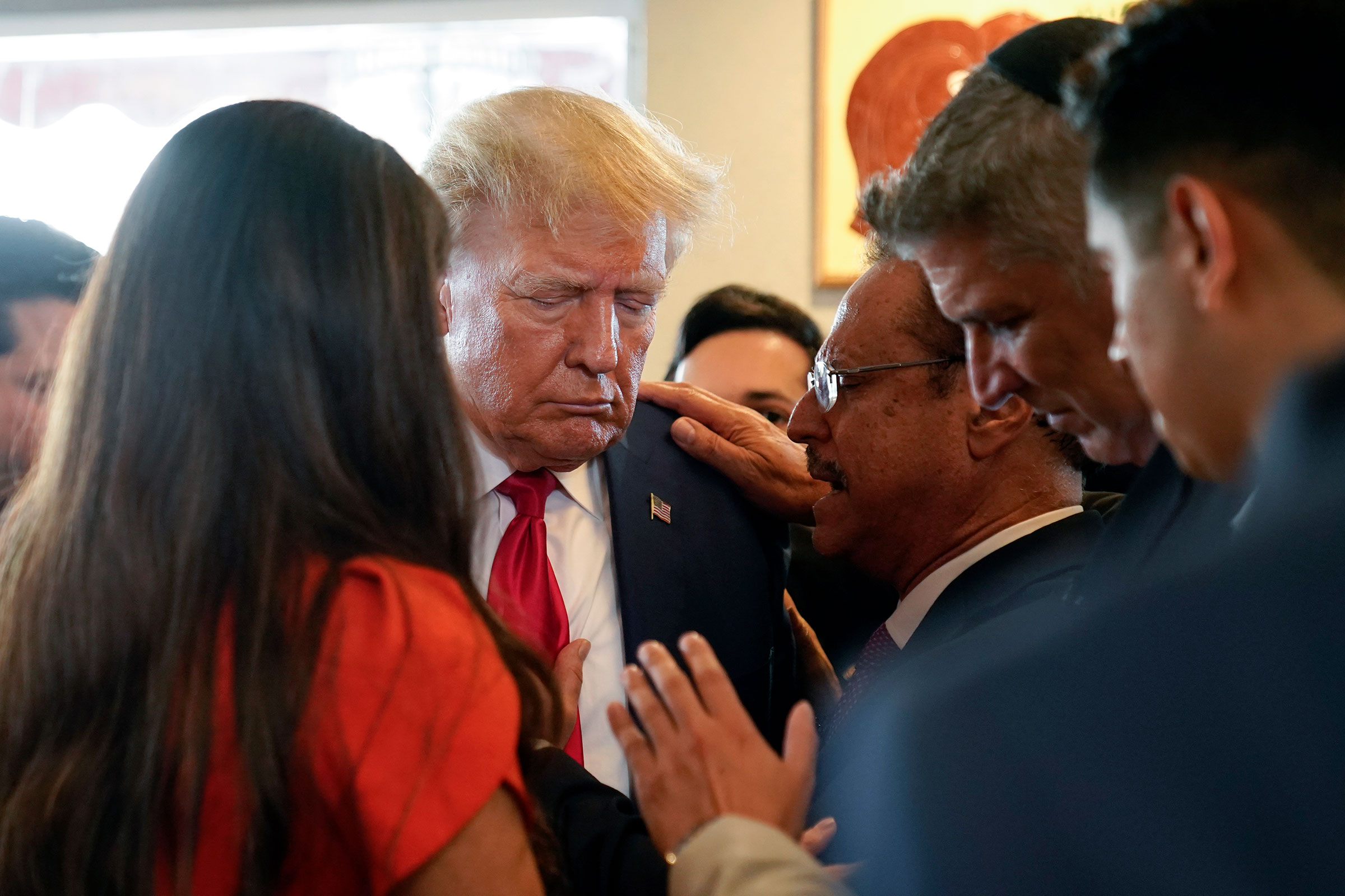 Former President Donald Trump prays with pastor Mario Bramnick, third from right, and others at Versailles restaurant on Tuesday, June 13, in Miami. 