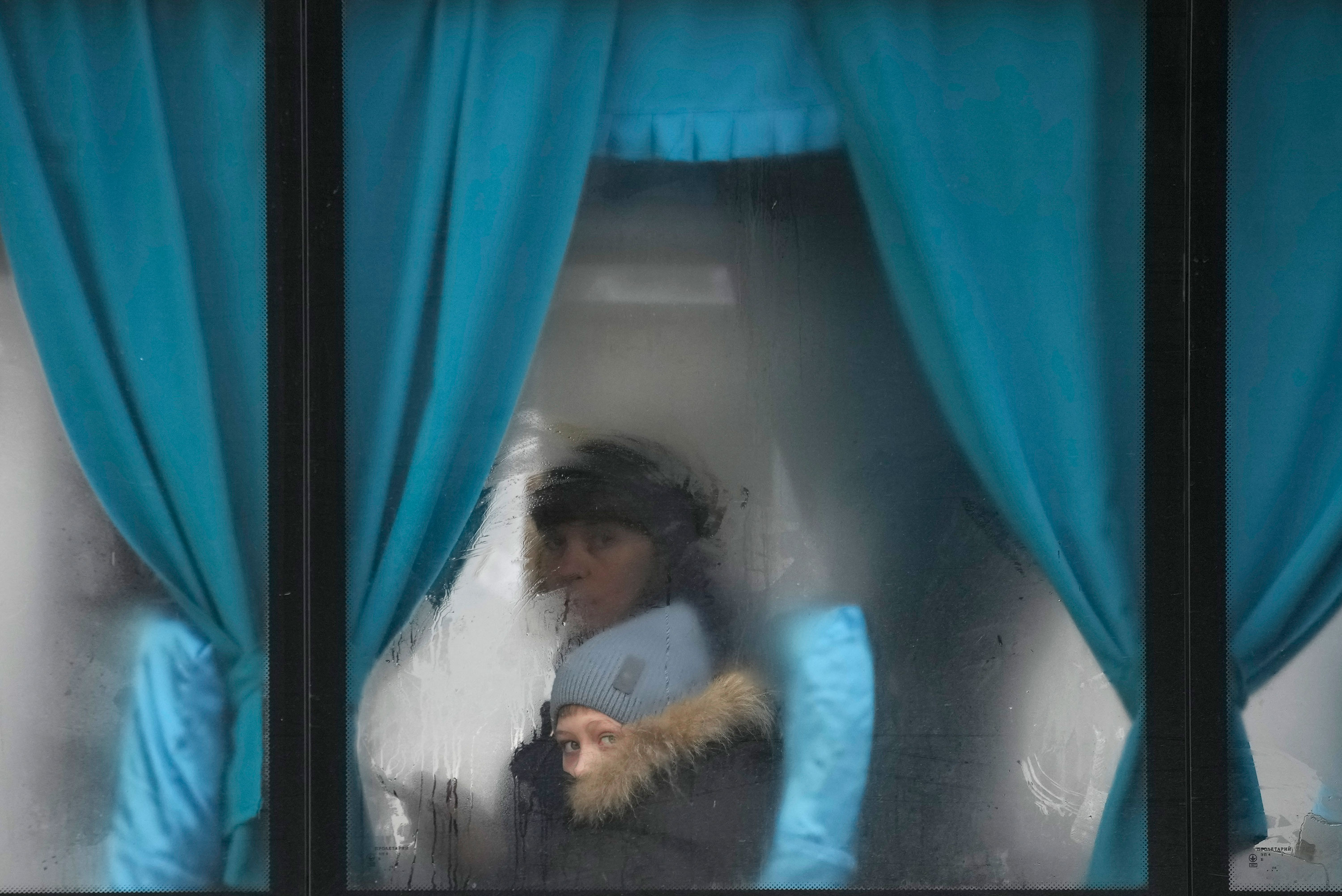 A woman and child peer out of the window of a bus as they leave Sievierodonetsk in the Luhansk region of Ukraine on Thursday, February 24.
