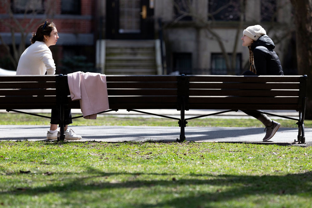 Two women practice social distancing while talking in Boston, Massachusetts, on April 4.