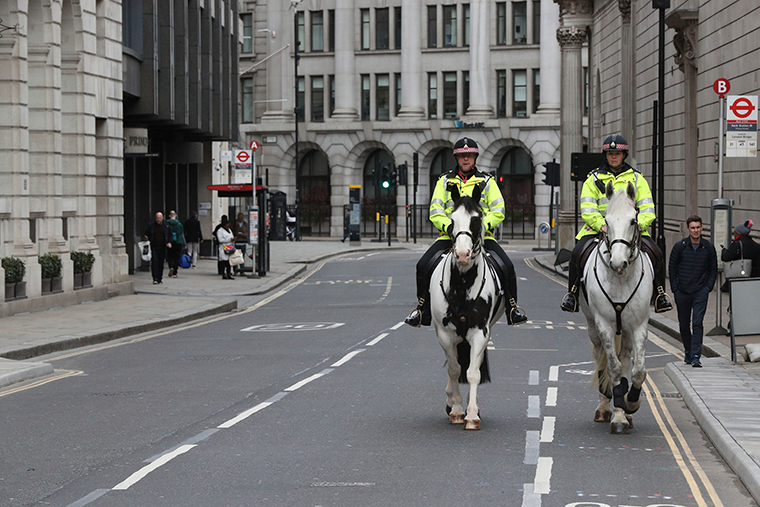 Mounted police patrol a quiet street in the City of London, adopting social distancing on horseback, as the UK's coronavirus epicentre is concentrated in London, Friday March 20. 