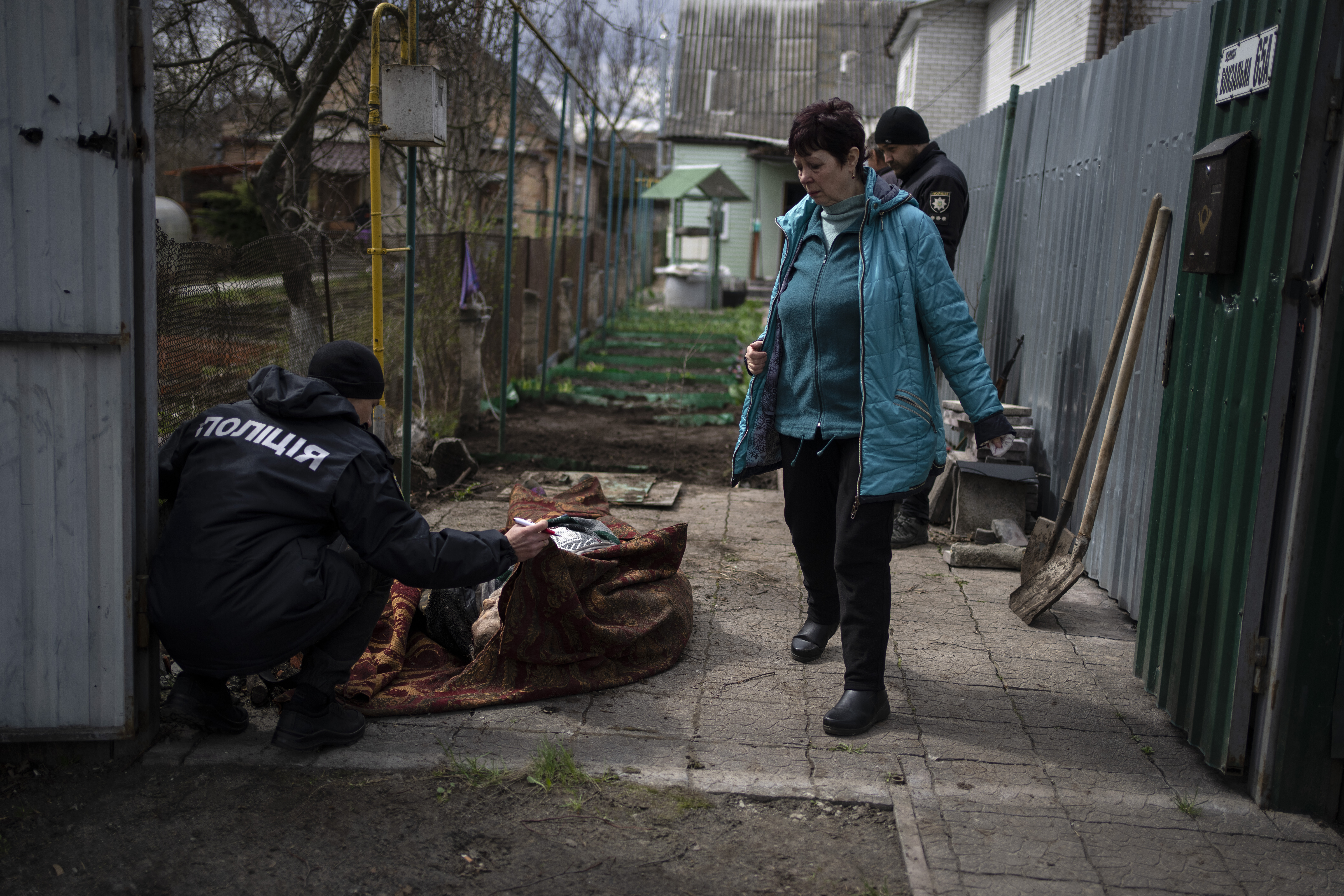 A police officer examines the corpse of a man killed during the war with Russia, in Bucha, located on the outskirts of Kyiv, Ukraine, on April 11.