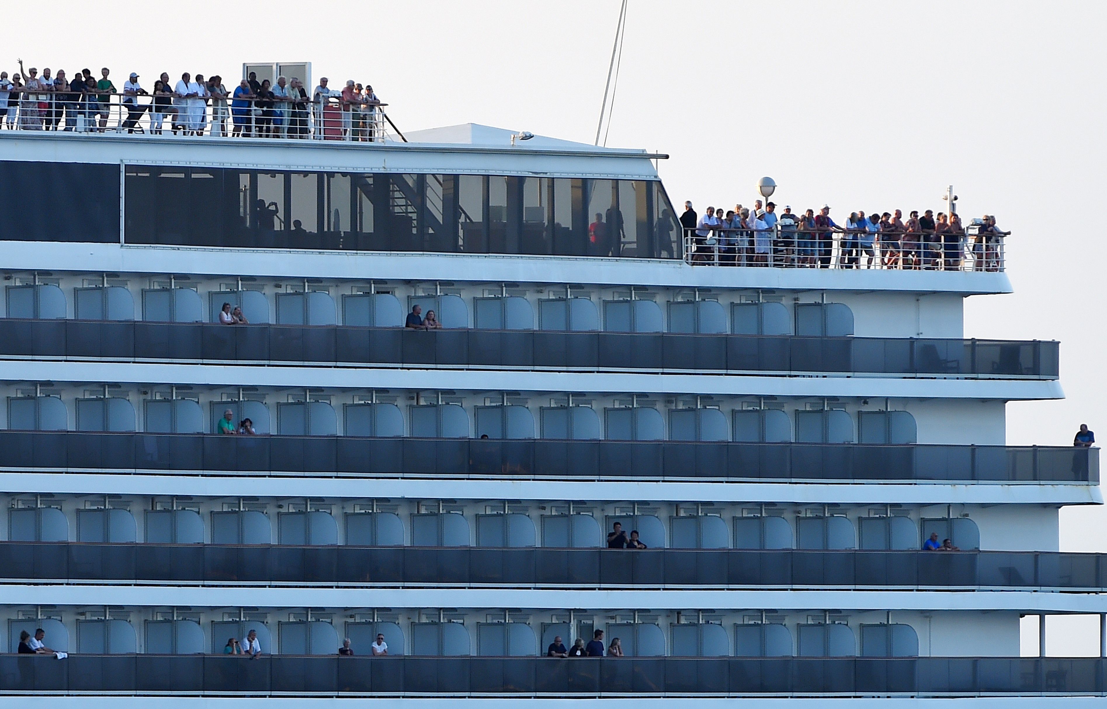 Passengers watch as the Westerdam cruise ship approaches the port in Sihanoukville on Cambodia's southern coast on Feb. 13, where the liner had received permission to dock after being refused entry at other Asian ports due to fears of the COVID-19 coronavirus.