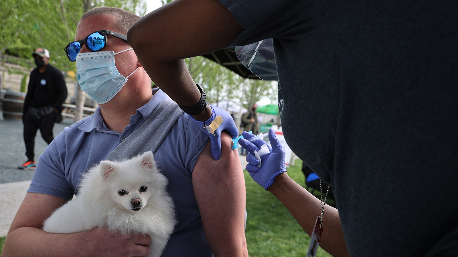 A man holds his emotional support dog, named 'Rhea,' as he receives a dose of the Johnson & Johnson coronavirus vaccine during a walk-up clinic at the Kennedy Center's outdoor Reach area on May 6 in Washington, DC.