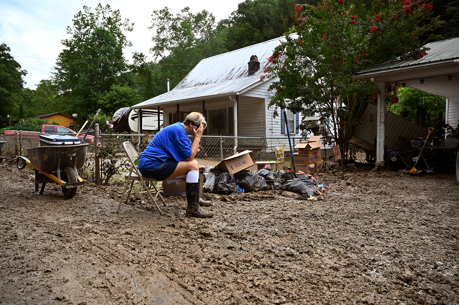 Teresa Reynolds sits exhausted as members of her community clean the debris from their flood ravaged homes at Ogden Hollar in Hindman, Ky., on Saturday, July 30.