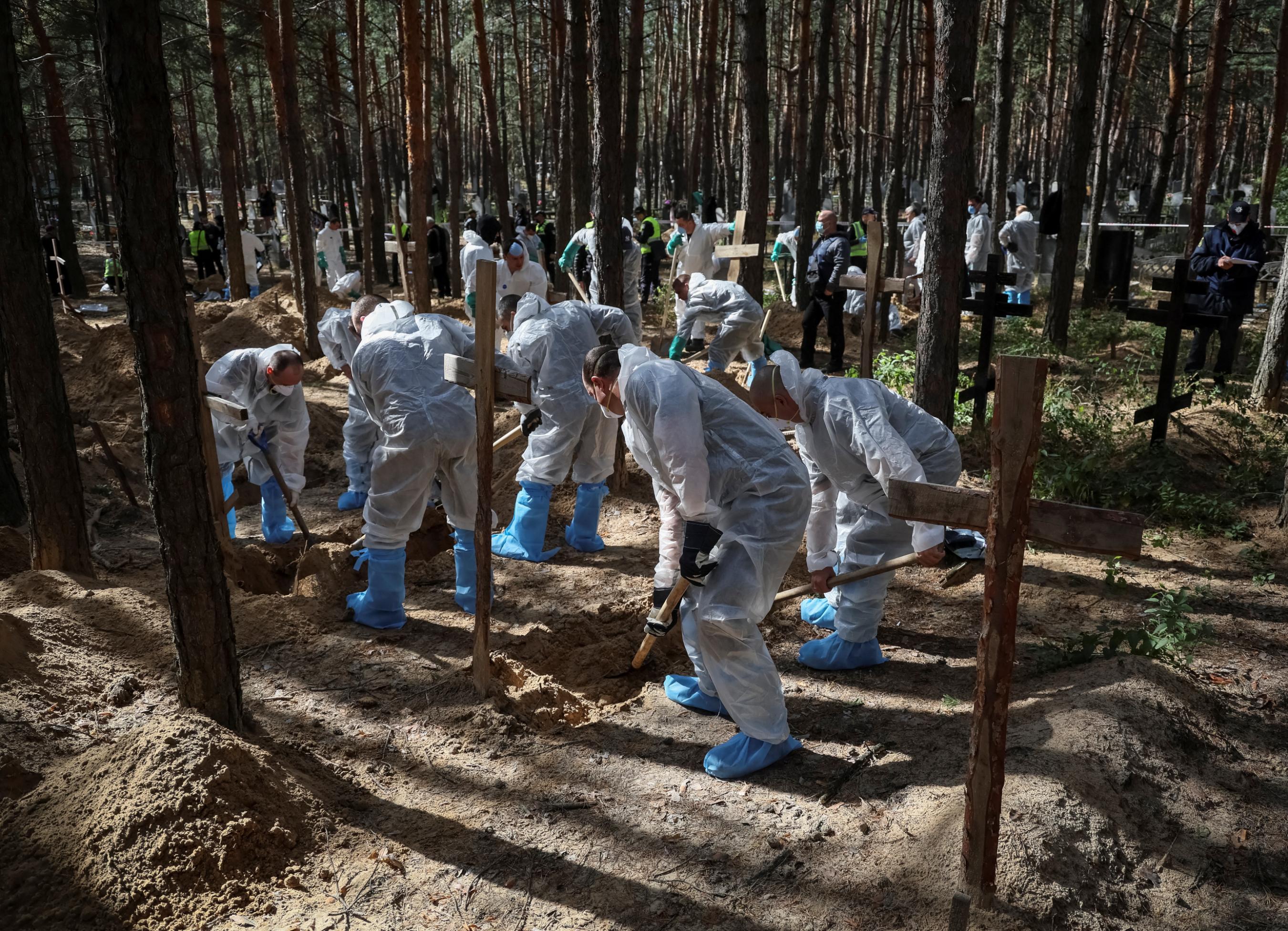 Ukrainian Emergency Service members work at a mass burial site in Izium, Ukraine, on September 19. 