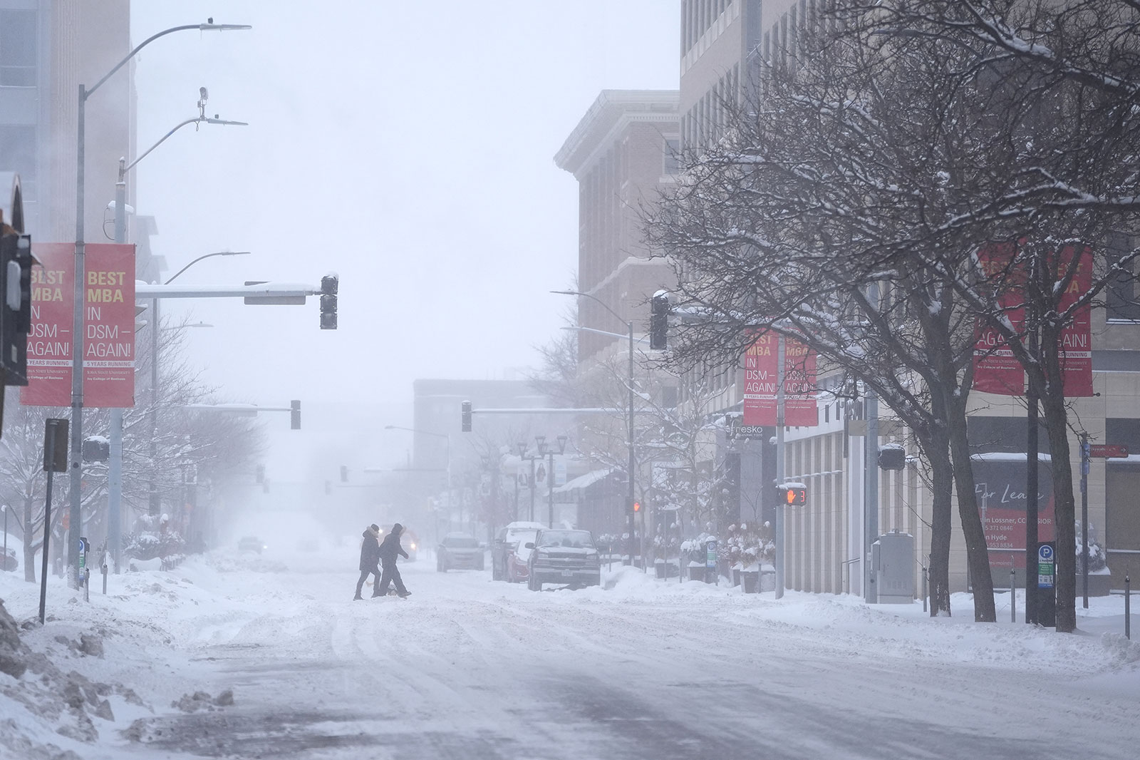 Pedestrians cross the street in snowy conditions on Friday in Des Moines, Iowa. 