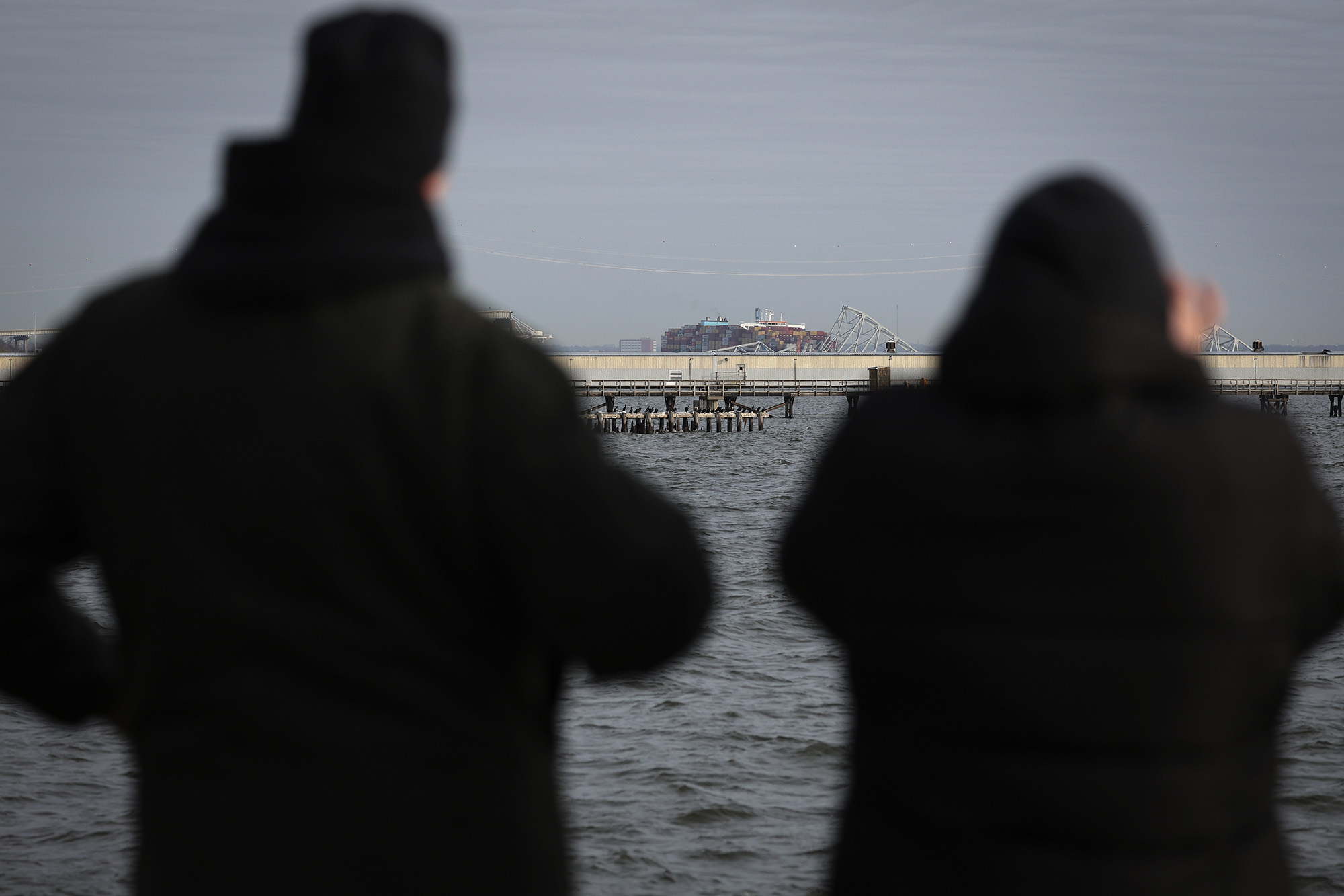 Local residents watch as a cargo ship is shown after running into and collapsing the Francis Scott Key Bridge on March 26, in Baltimore, Maryland. 