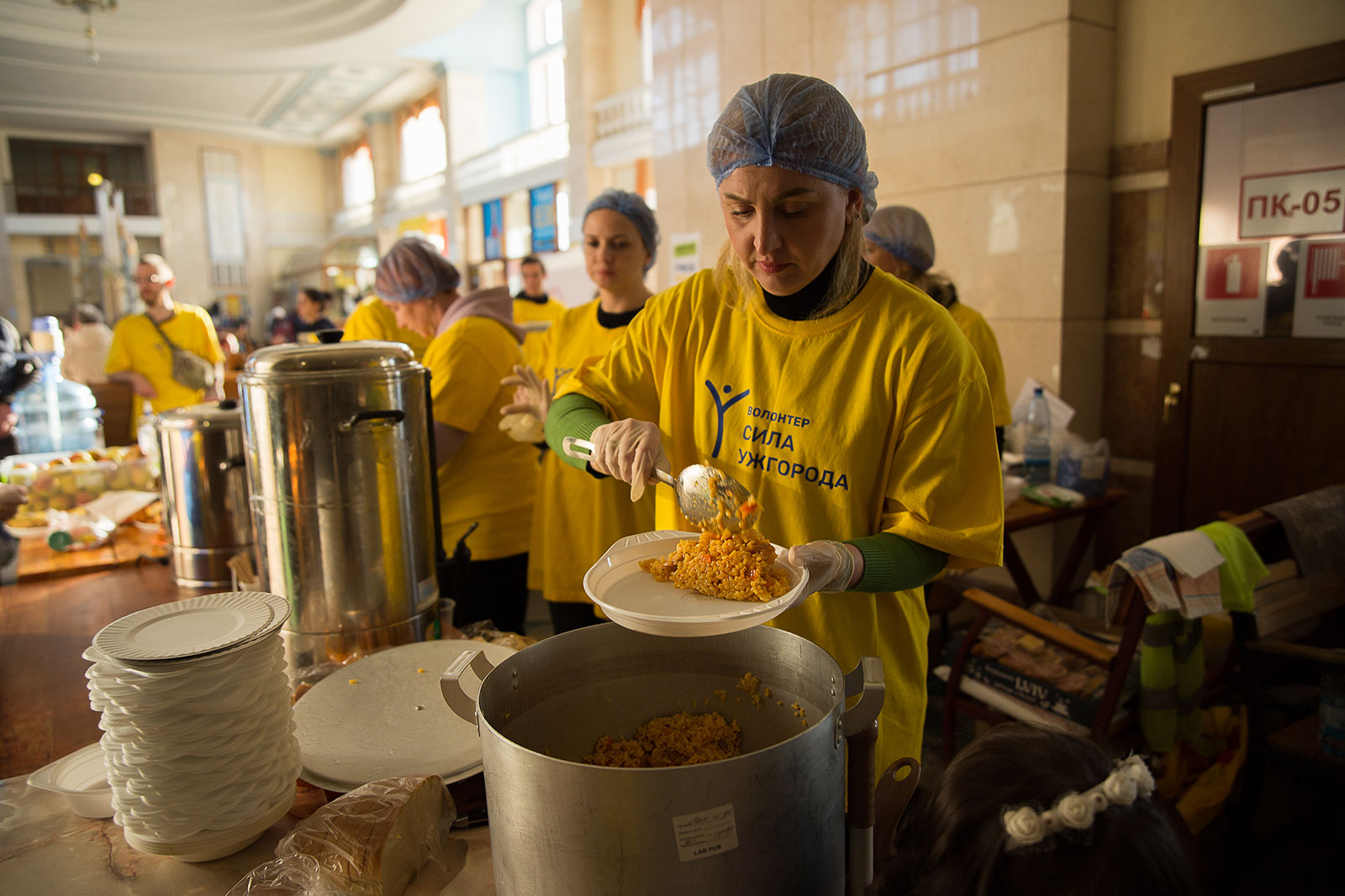A volunteer from the initiative 'Sila Uzhhoroda' (The Power of Uzhhorod) serves meals to fleeing refugees at Uzhhorod train station on March 24 in Uzhhorod, Ukraine.