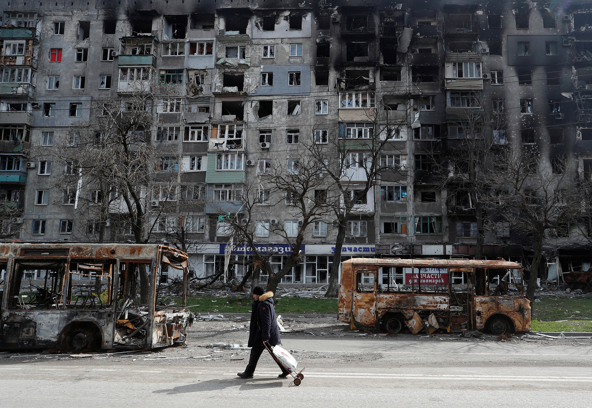 A local resident walks along a street past destroyed buses and buildings in the southern port city of Mariupol, Ukraine, on April 19.