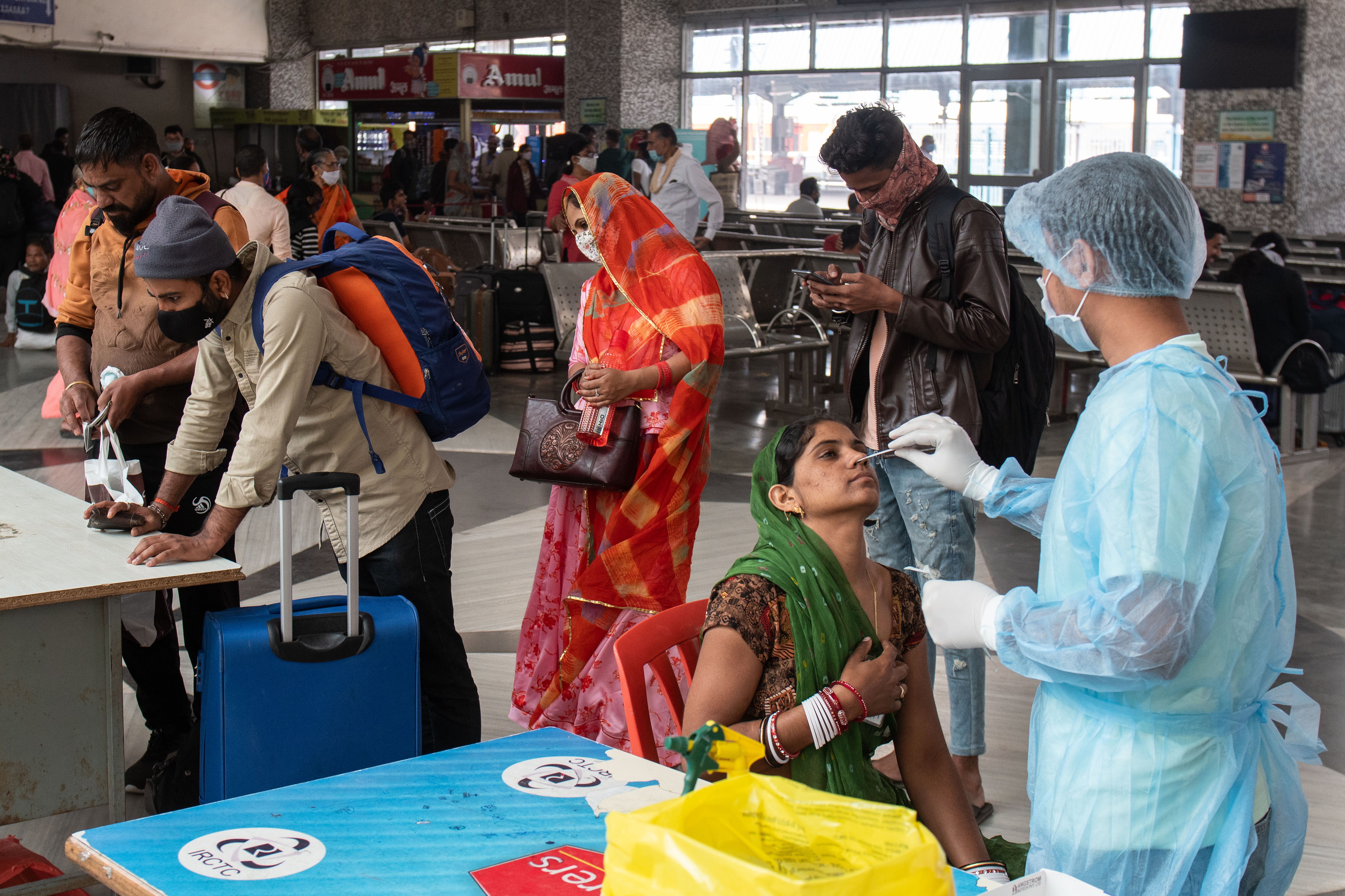 Medical staff collect swab samples to test for Covid-19 from passengers arriving on station trains at Bandra Terminus, on December 16, 2021 in Mumbai, India. 