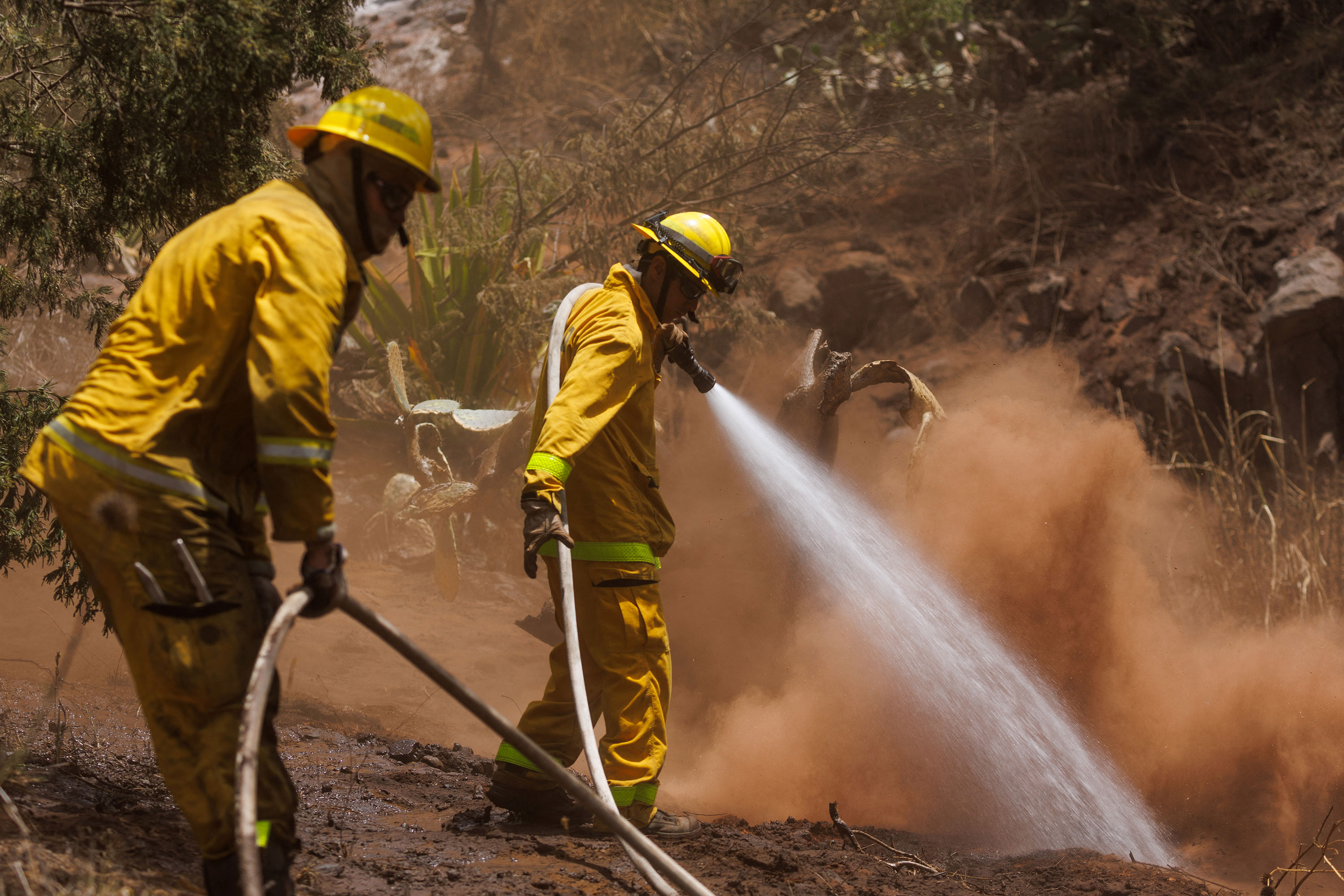 Maui County firefighters douse a flare-up in a canyon in Kula on Sunday.