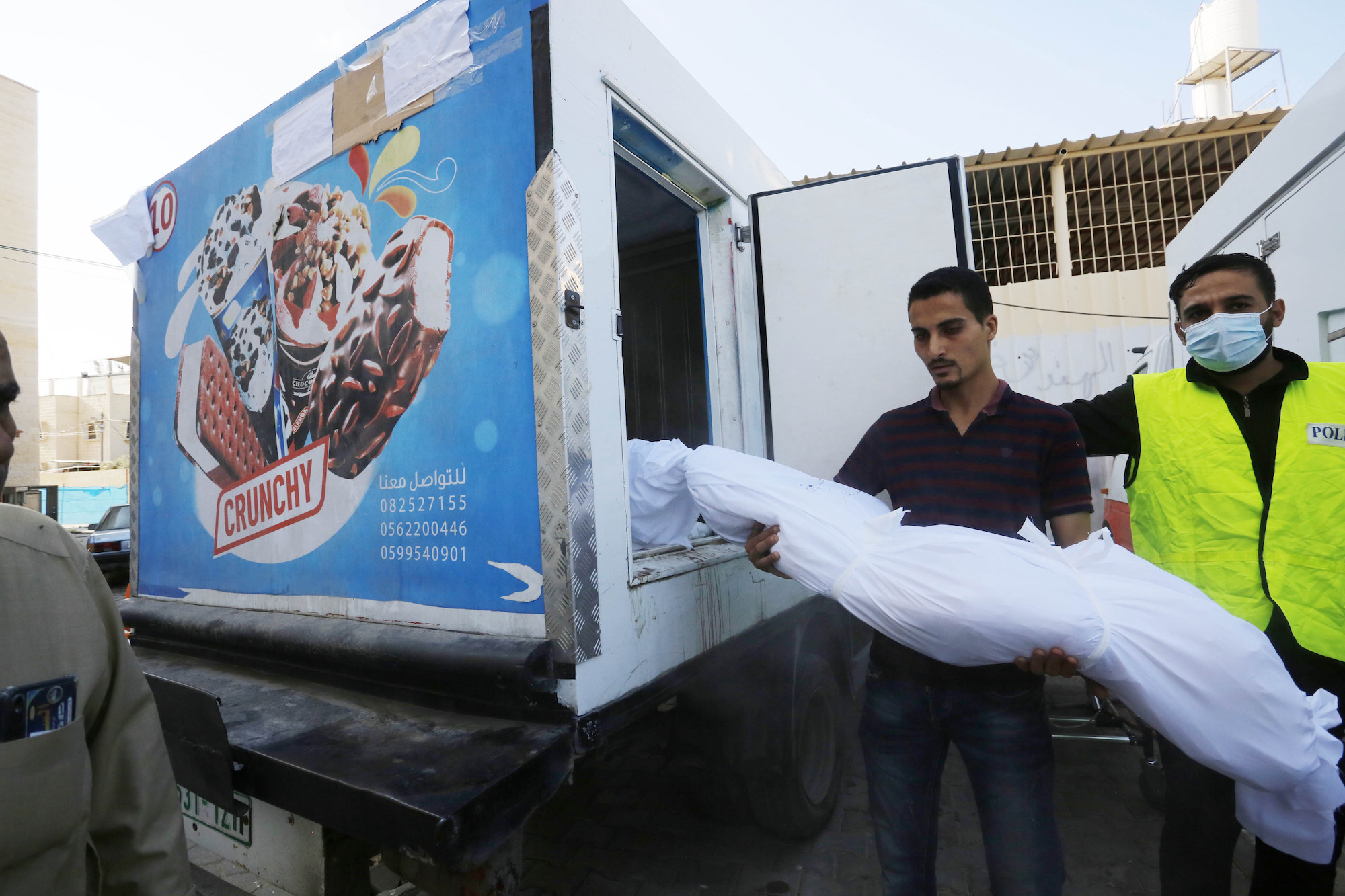 A man carries a body to an ice cream truck due to the insufficiency of hospital morgues at the Suheda al-Aqsa Hospital in Gaza on Saturday.