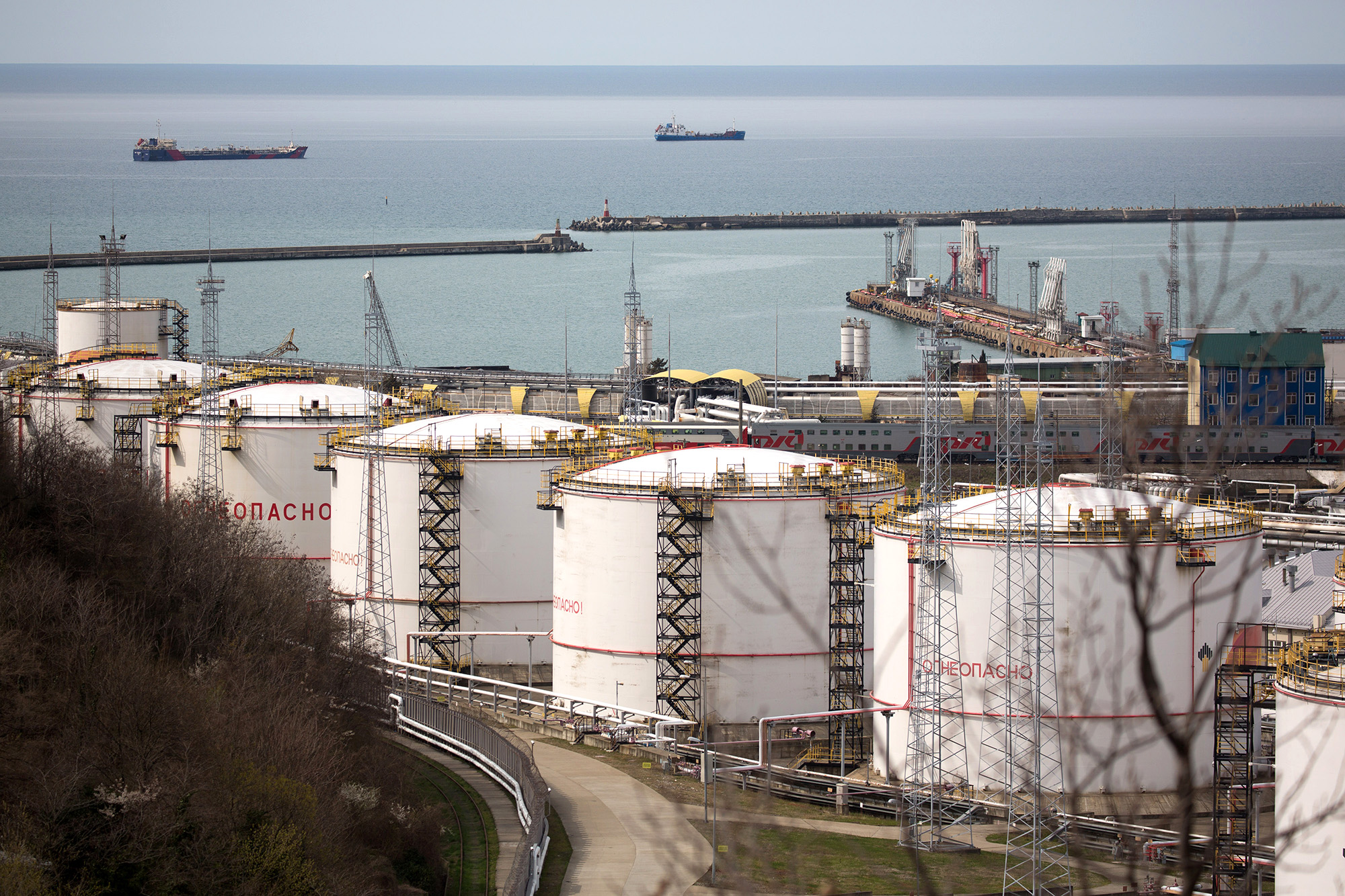 Oil storage tanks stand at the RN-Tuapsinsky refinery, operated by Rosneft Oil Co., as tankers sail beyond in Tuapse, Russia, on March 23, 2020.