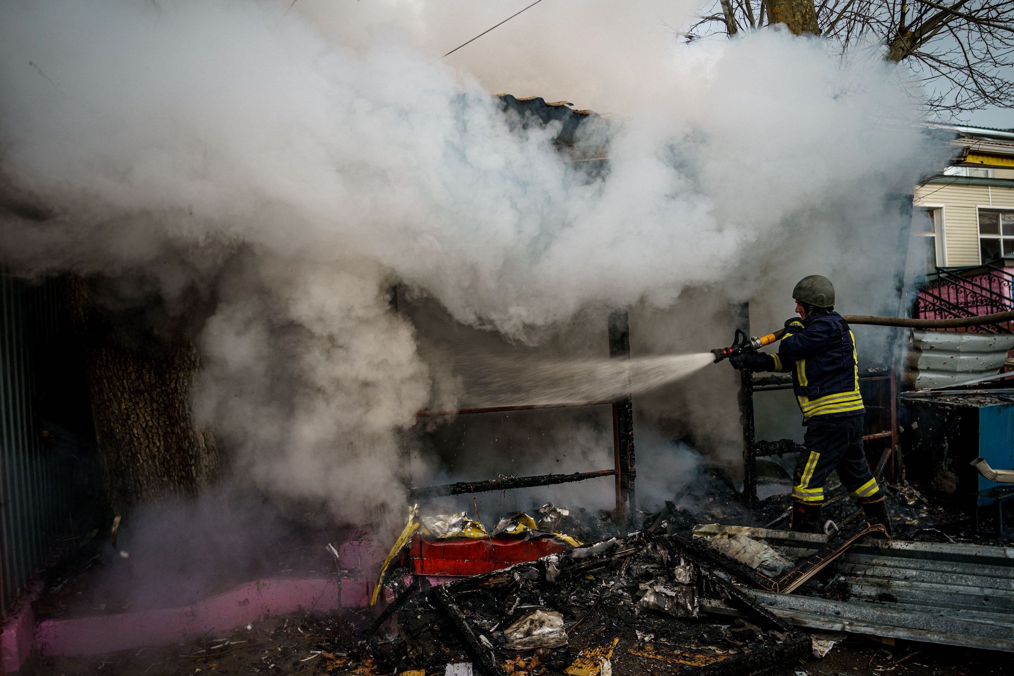 Seorang petugas pemadam kebakaran memadamkan toko yang terbakar setelah penembakan Rusia di Kherson pada 24 Desember.
