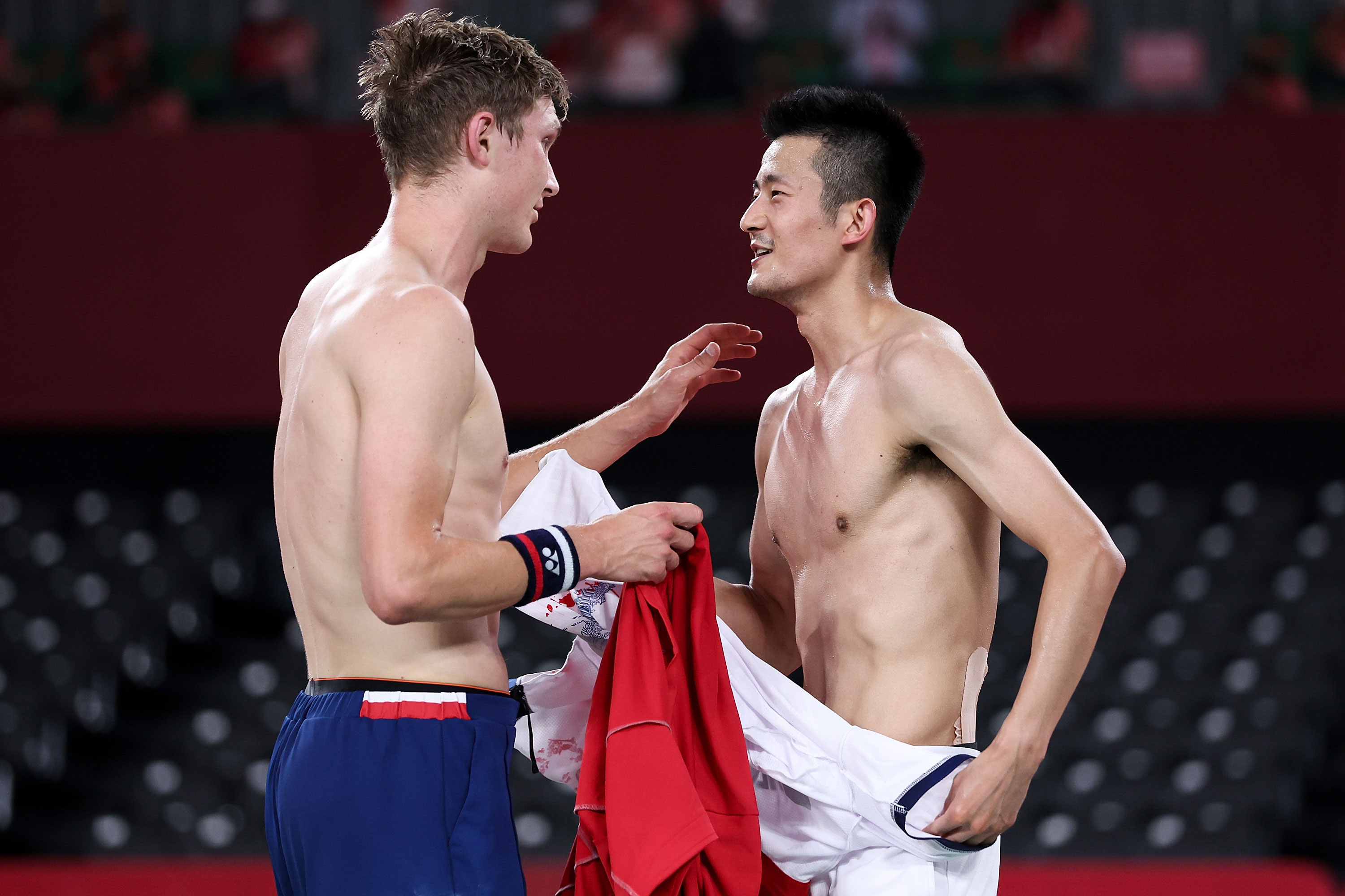 Viktor Axelsen of Denmark, left, speaks with Chen Long of China after their badminton singles final on August 2.