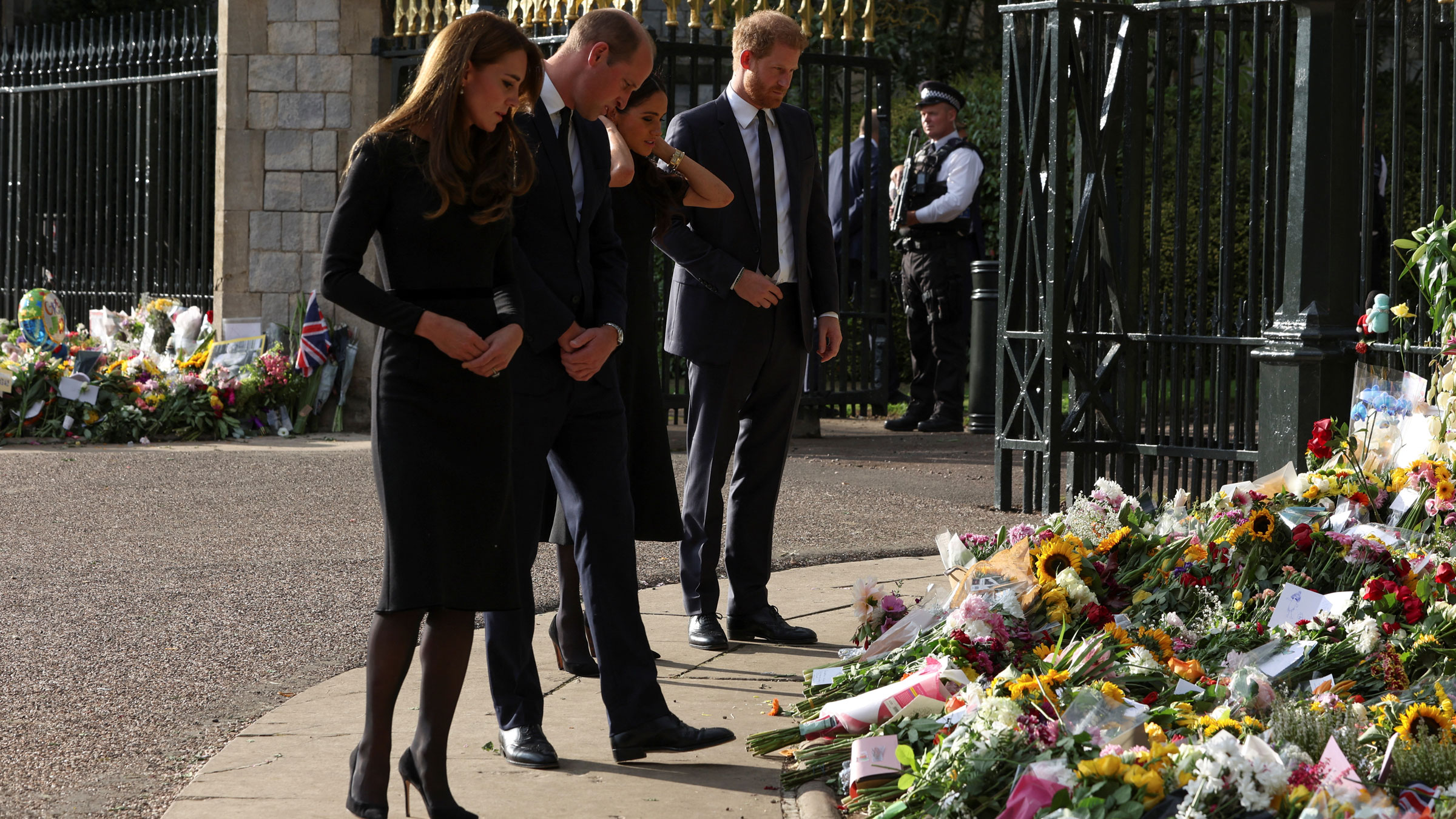 From left, Catherine, the Princess of Wales; Prince William; Meghan, the Duchess of Sussex; and Prince Harry look at floral tributes as they walk outside Windsor Castle on Saturday.